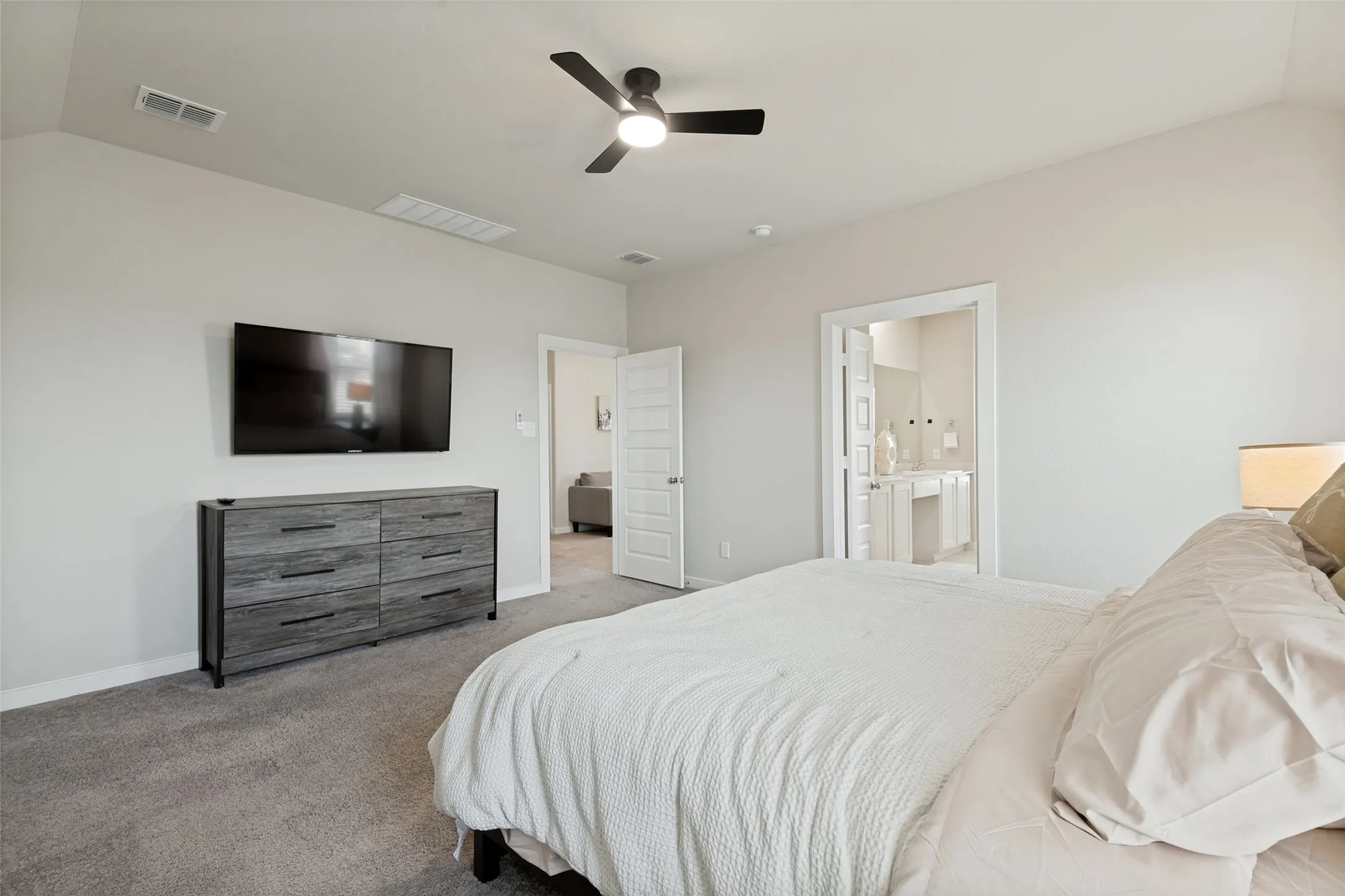 Vaulted ceilings with a central ceiling fan, neutral wall finishes, and solid-core interior doors