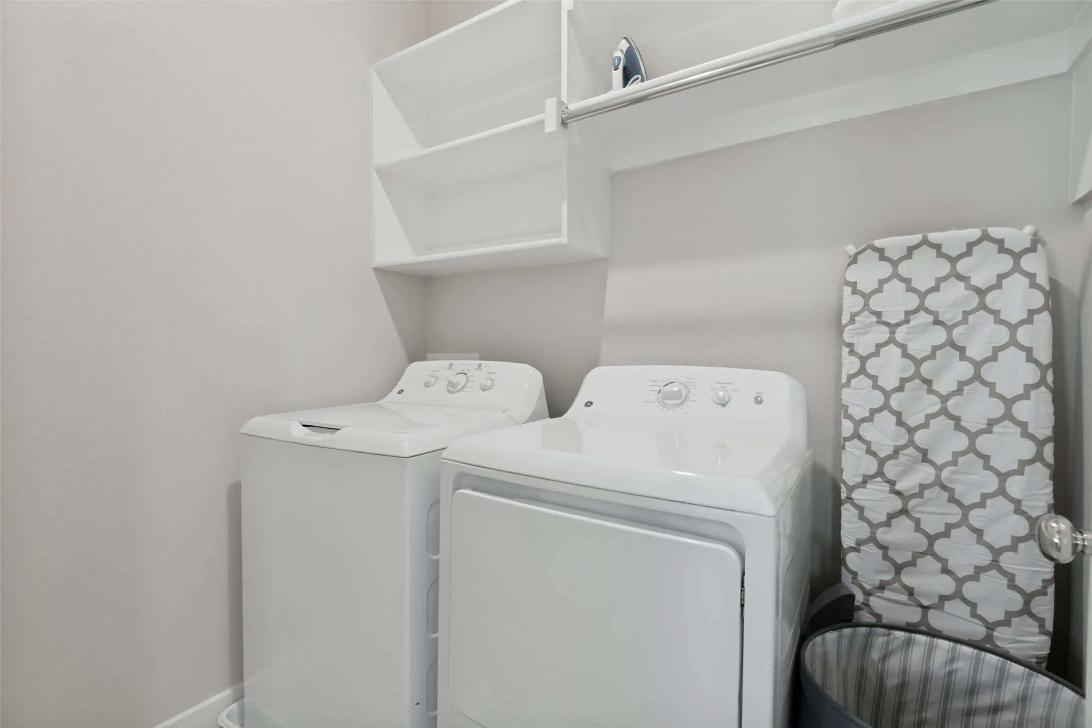 Laundry area featuring built-in white shelving, an integrated hanging rod, and neutral wall tones