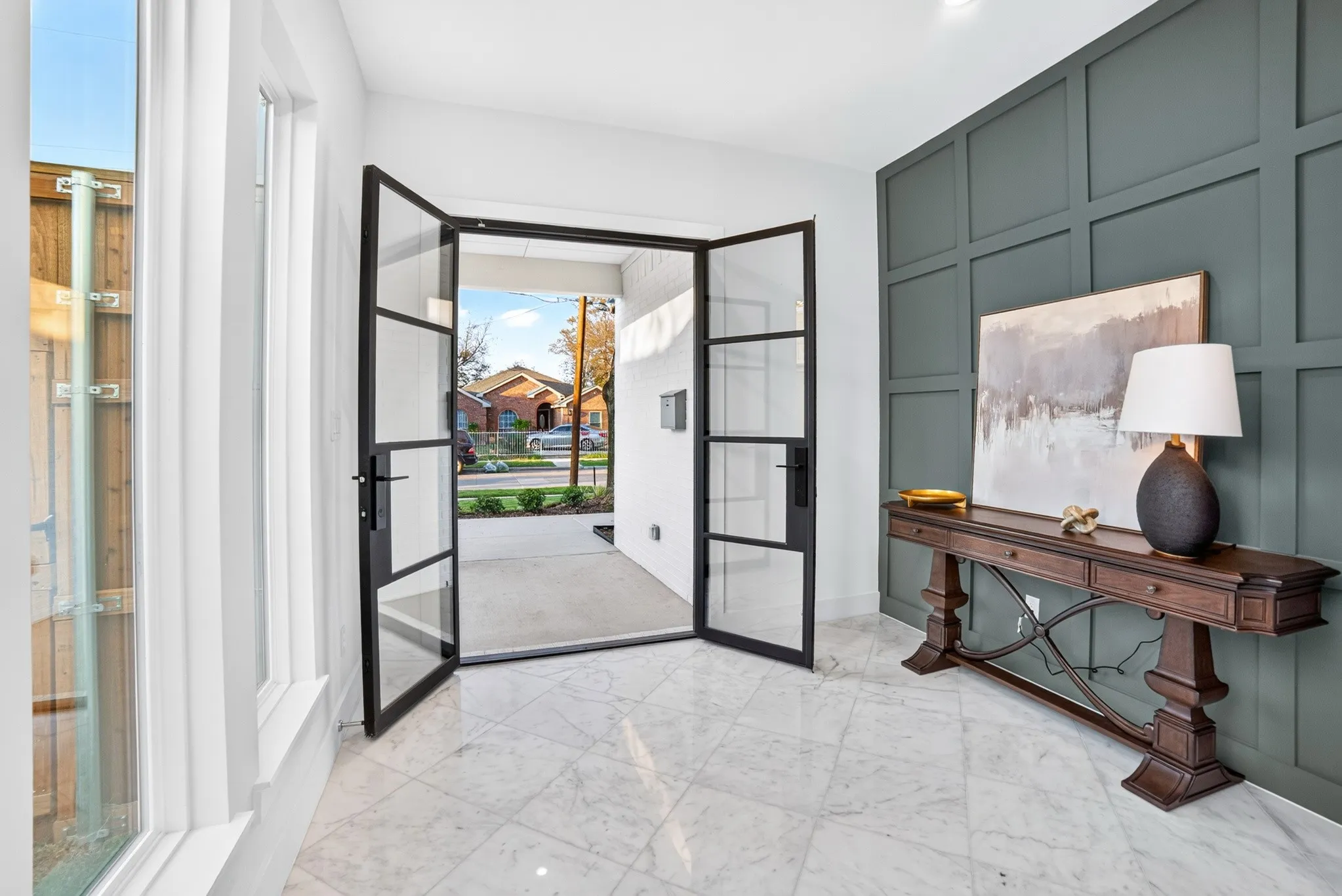 Entryway featuring a double-door glass entrance with black frames, tile flooring, and a large-scale paneled accent wall
