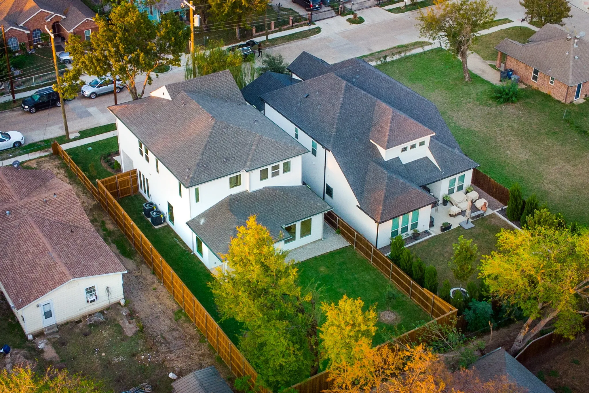 Multi-level residence featuring a light-toned exterior, hipped roofline, fenced backyard, and established landscaping