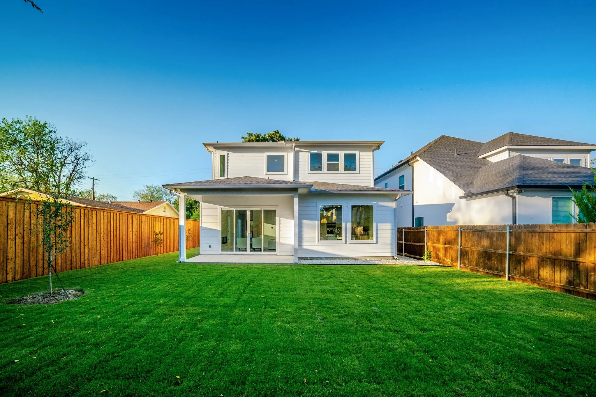 Rear exterior featuring horizontal siding, a covered concrete patio, multi-pane windows, and a fenced backyard with lawn