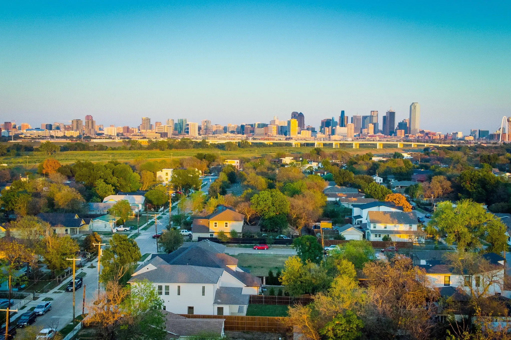 Aerial perspective featuring a panoramic city skyline, expansive tree-lined residential surroundings, and established street infrastructure