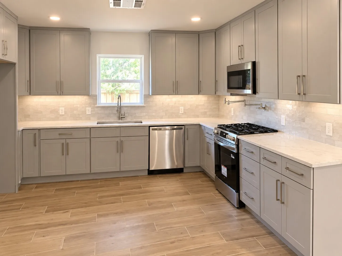 Kitchen featuring shaker-style cabinetry, light-toned stone-finish countertops, stainless steel appliances, a tile backsplash, and wood-finish flooring