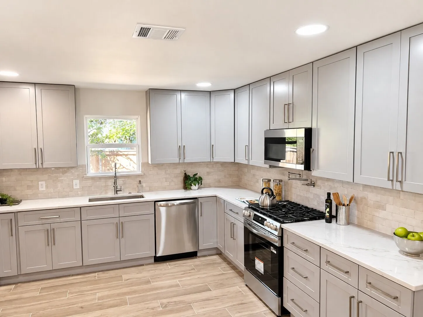 Kitchen featuring shaker-style cabinetry, stone-finish backsplash, stainless steel appliances, quartz countertops, and wood-finish flooring