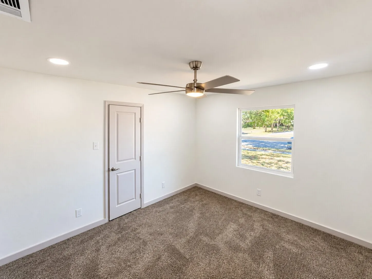 Room featuring neutral wall-to-wall carpeting, recessed ceiling lighting, a centrally located brushed-nickel ceiling fan with integrated light kit, and a single-panel interior door