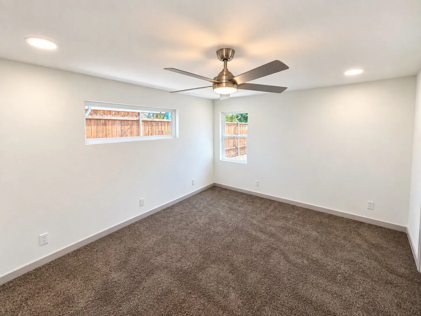 Neutral-toned carpeting, brushed nickel ceiling fan with integrated lighting, recessed ceiling lighting, and dual vinyl-framed windows