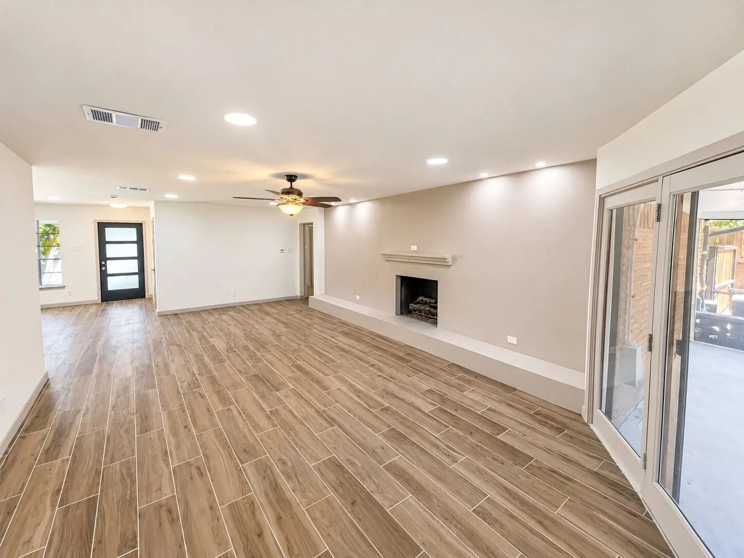 Interior featuring wood-finish tile flooring, a fireplace with a concrete hearth, recessed ceiling lighting, a ceiling fan, and sliding glass patio doors