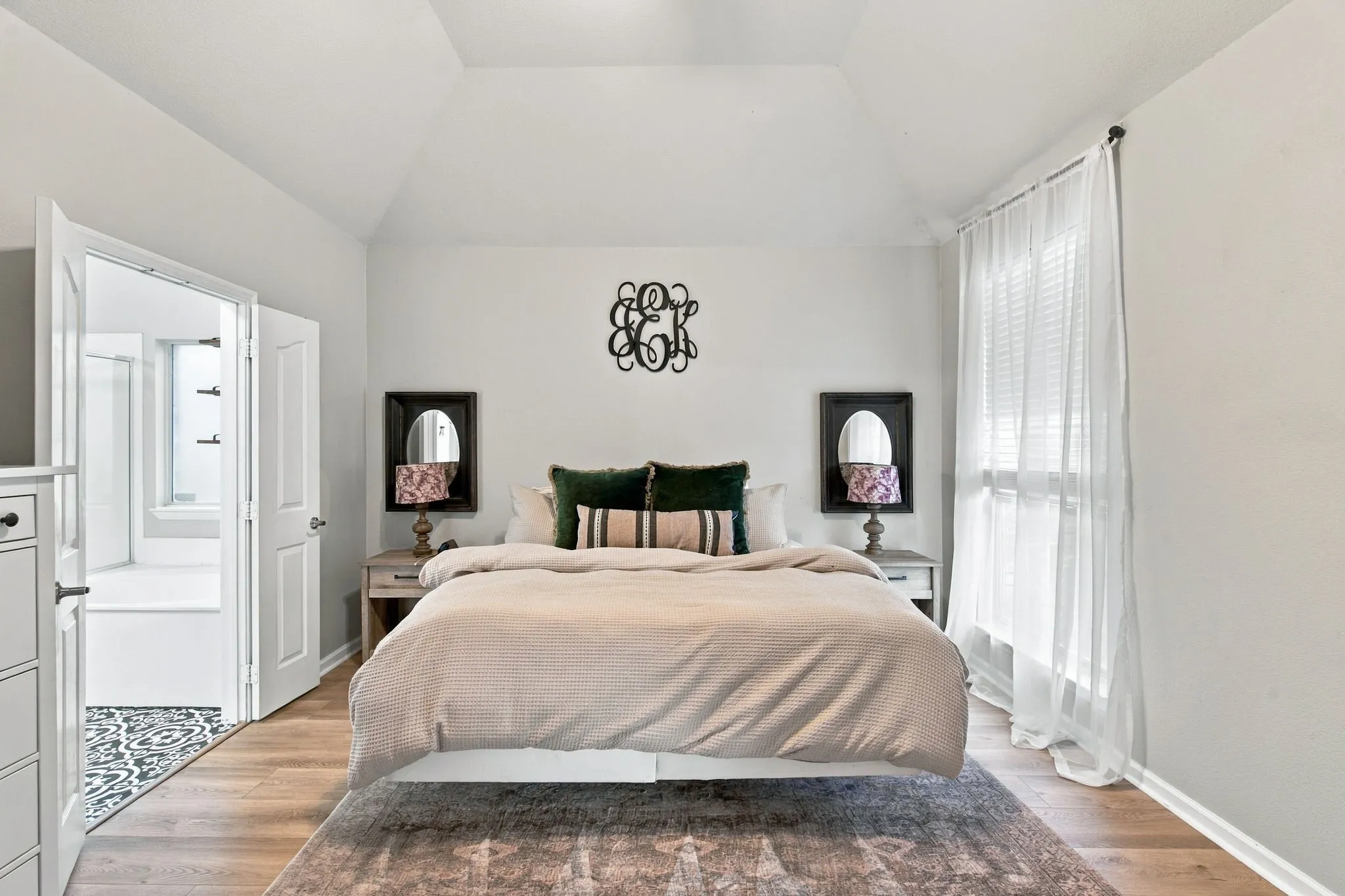 Bedroom featuring a vaulted ceiling, wood-finish flooring, and a large window