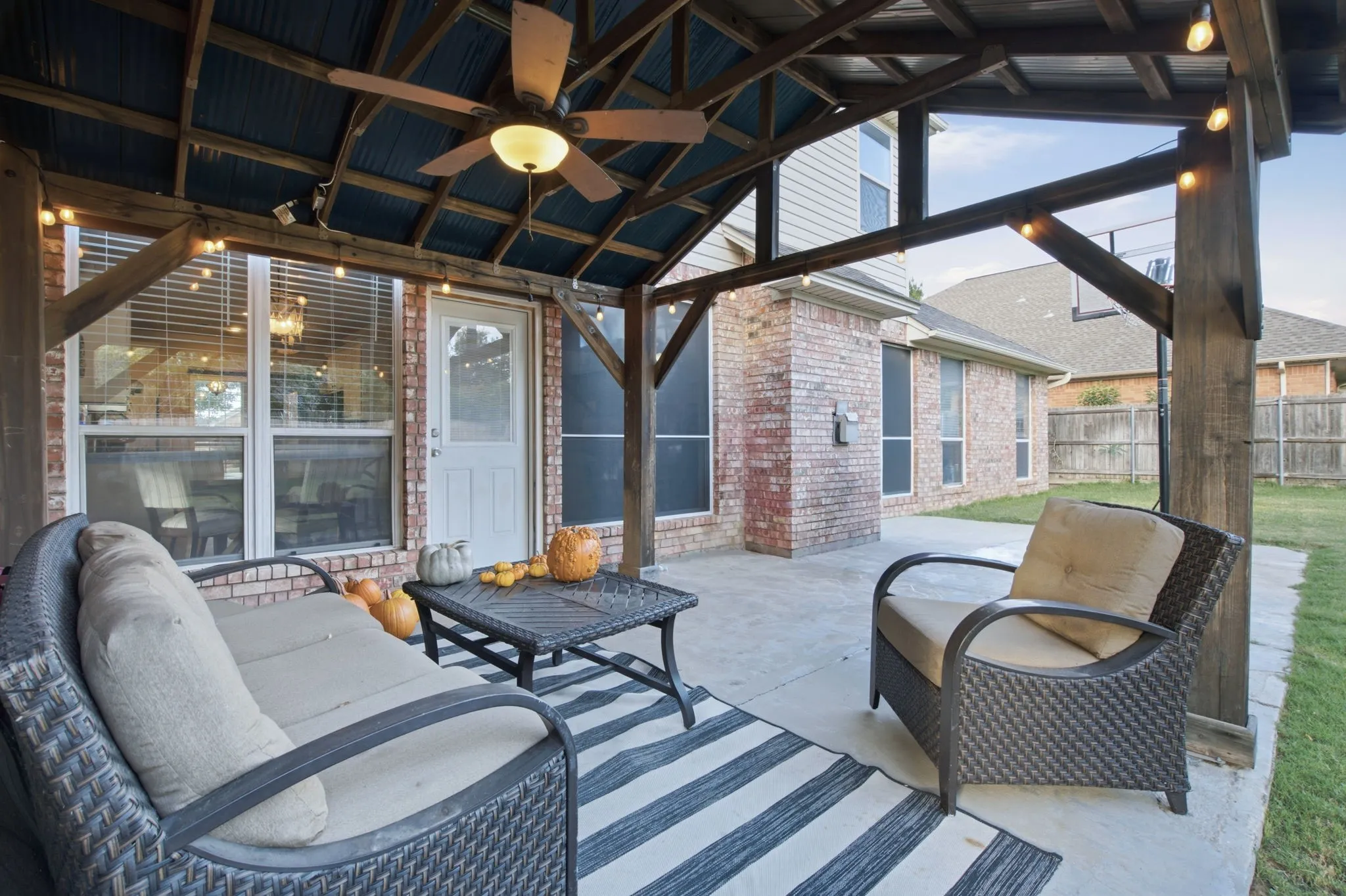 Covered patio featuring a timber-frame pergola, concrete flooring, and a ceiling-mounted fan with integrated lighting