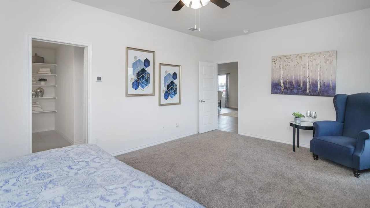 Spacious room with plush carpet flooring, a ceiling fan with integrated lighting, and a walk-in closet featuring built-in shelving