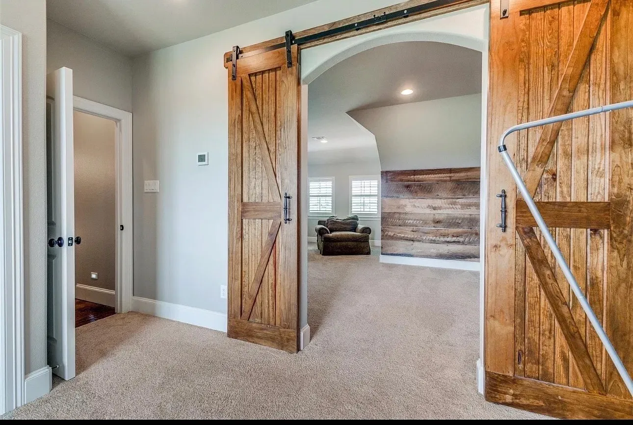 Arched entryway featuring custom wood barn doors with matte black hardware and a decorative wood-plank accent wall