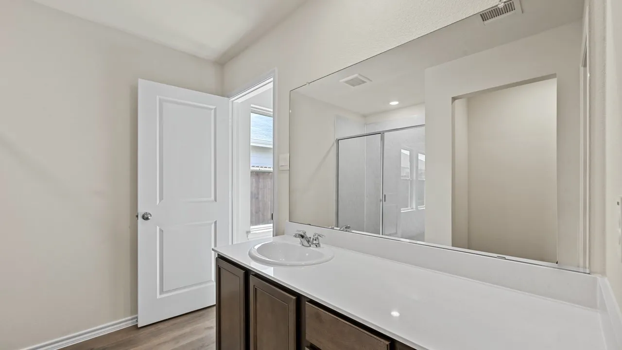 Vanity with a single basin sink, expansive mirror, wood-finish flooring, and a two-panel interior door