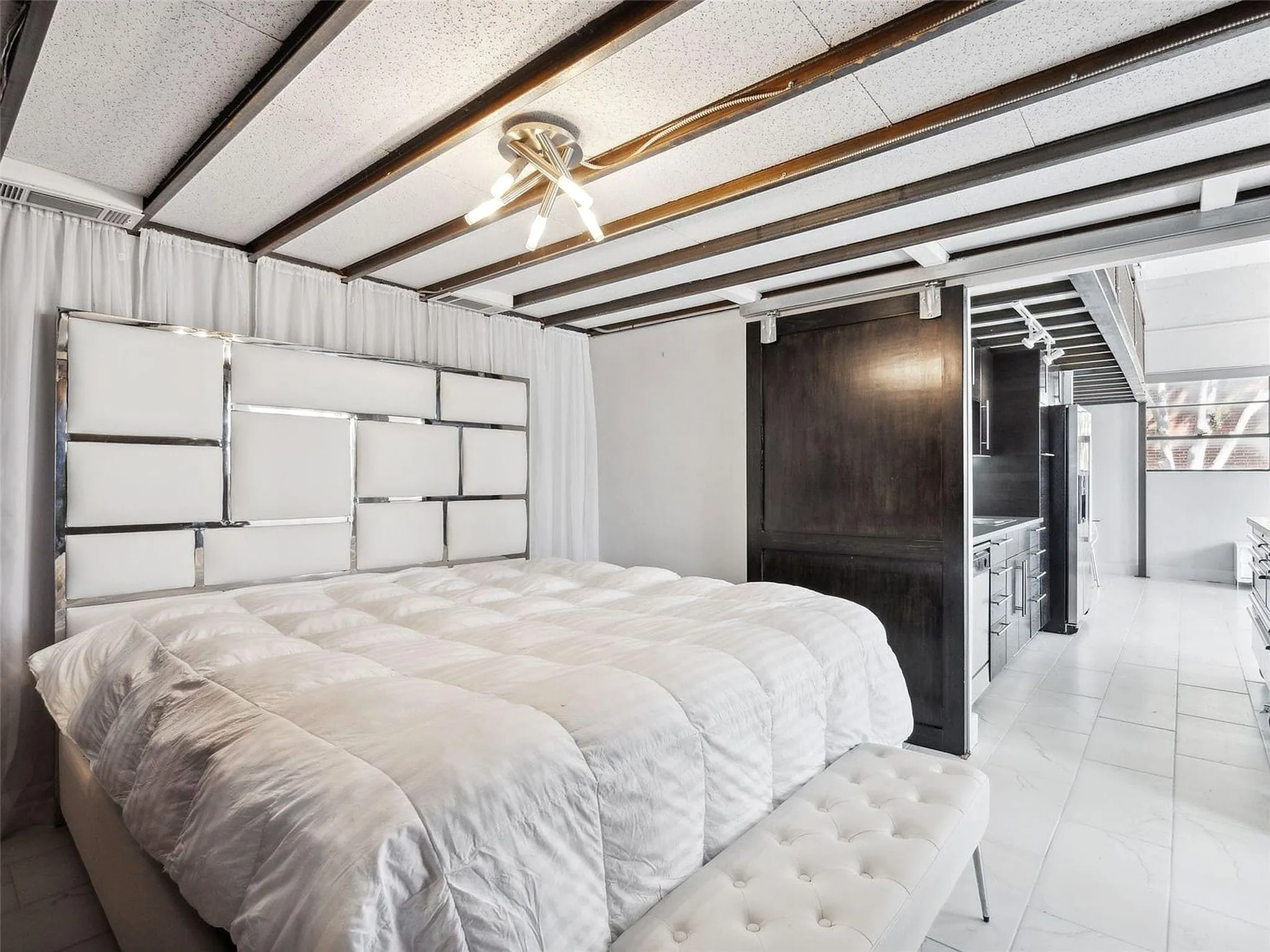 Exposed beam ceiling with recessed lighting, dark wood sliding barn door, and large-format tile flooring