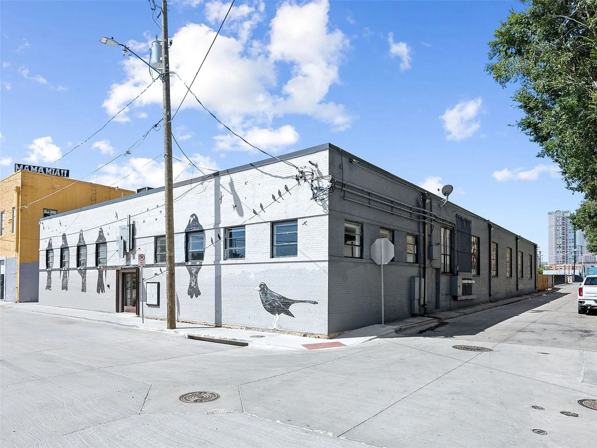 Commercial structure featuring a painted masonry exterior, multiple rectangular window openings, and street-level access