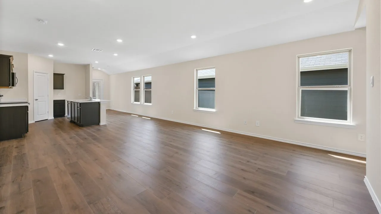 Open-concept living area featuring wood-finish flooring, recessed lighting, and multiple windows