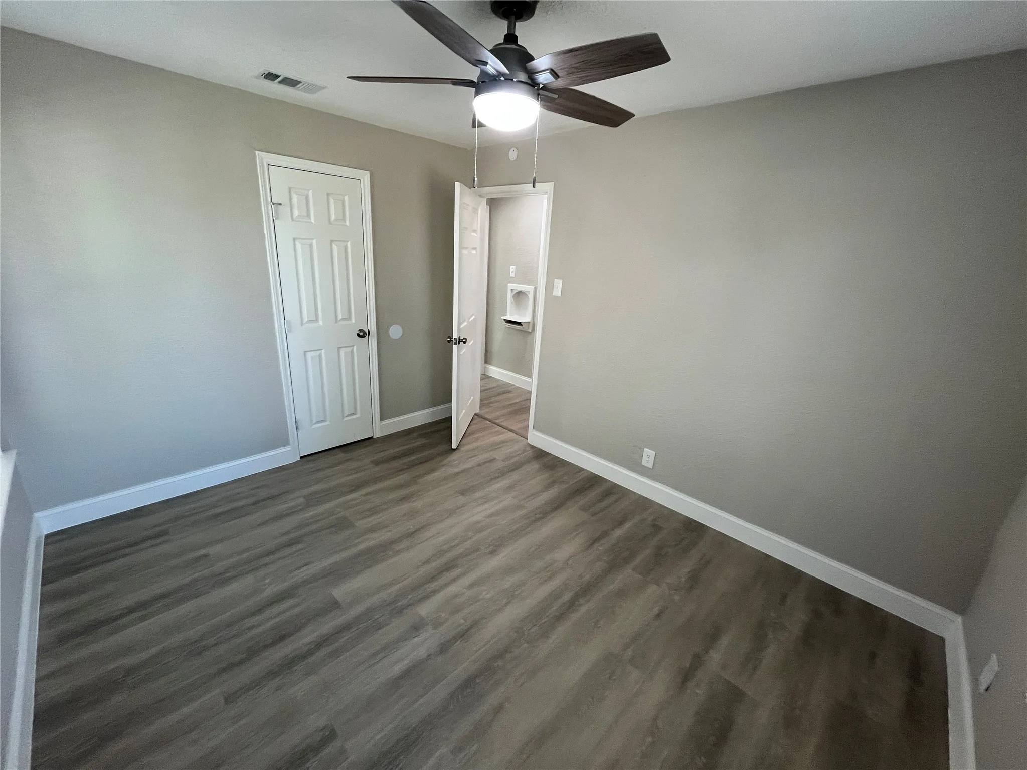 Wood-finish flooring, neutral wall tones, multi-panel doors, and a ceiling fan with integrated lighting fixture