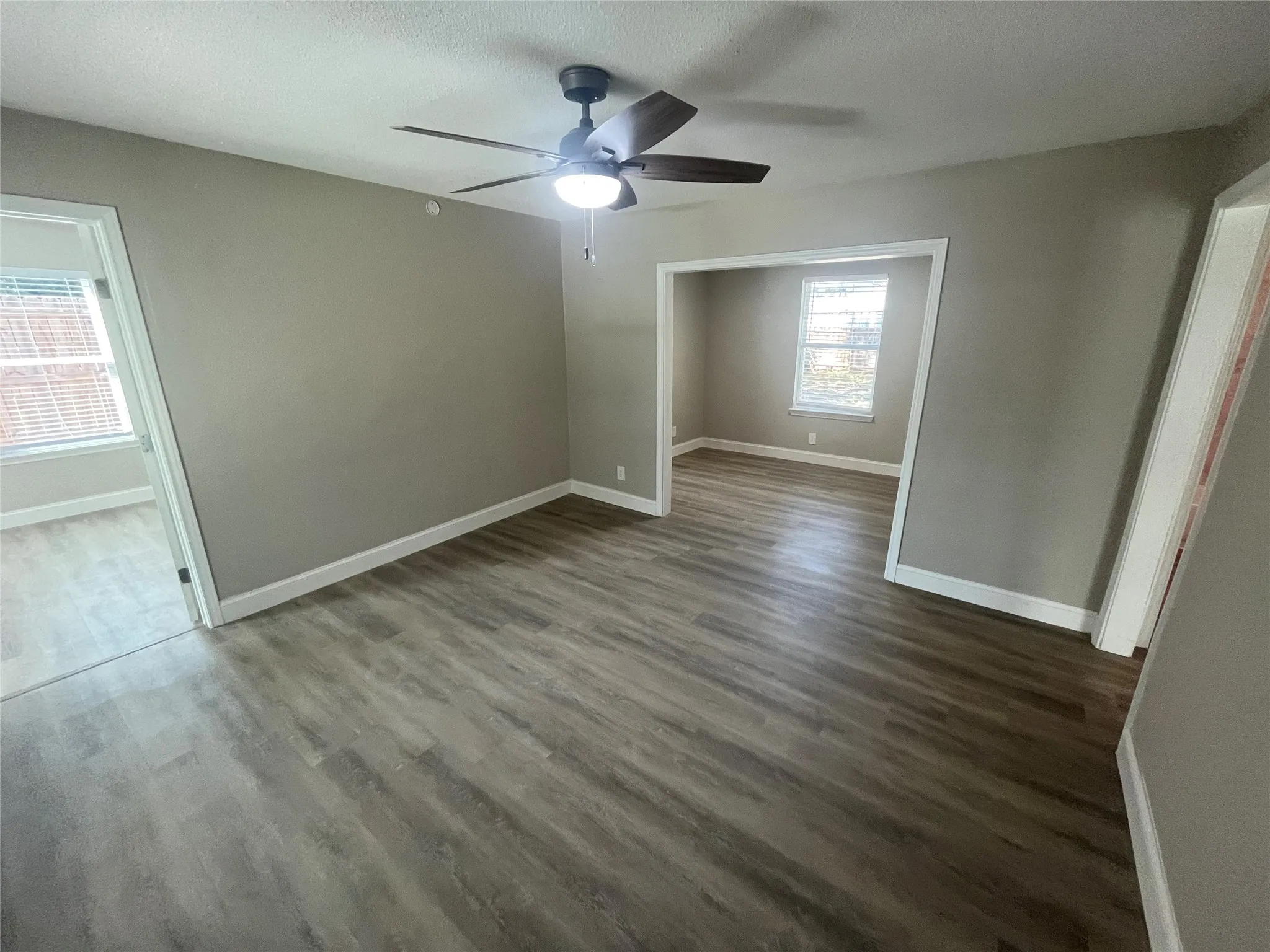 Interior space featuring wood-finish flooring, neutral wall paint, and a ceiling-mounted fan with integrated lighting
