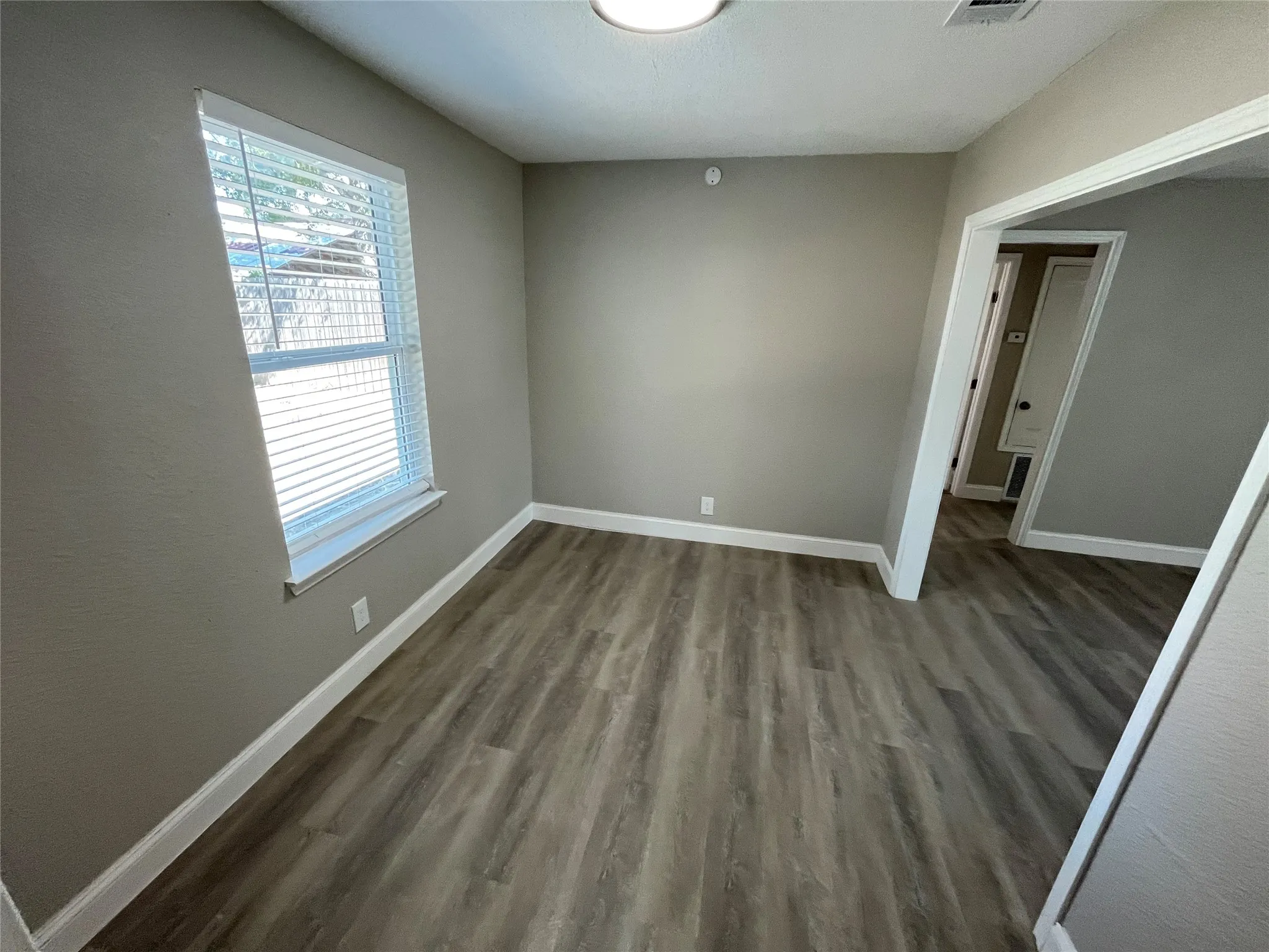 Room featuring neutral wall paint, wood-finish flooring, and a window with blinds
