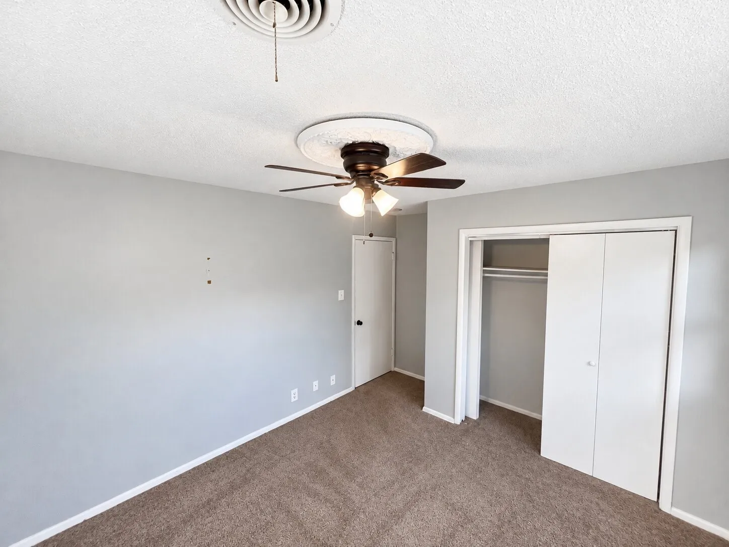 Neutral-toned room featuring wall-to-wall carpeting, a central ceiling fan with an integrated light fixture, and a white bifold closet door