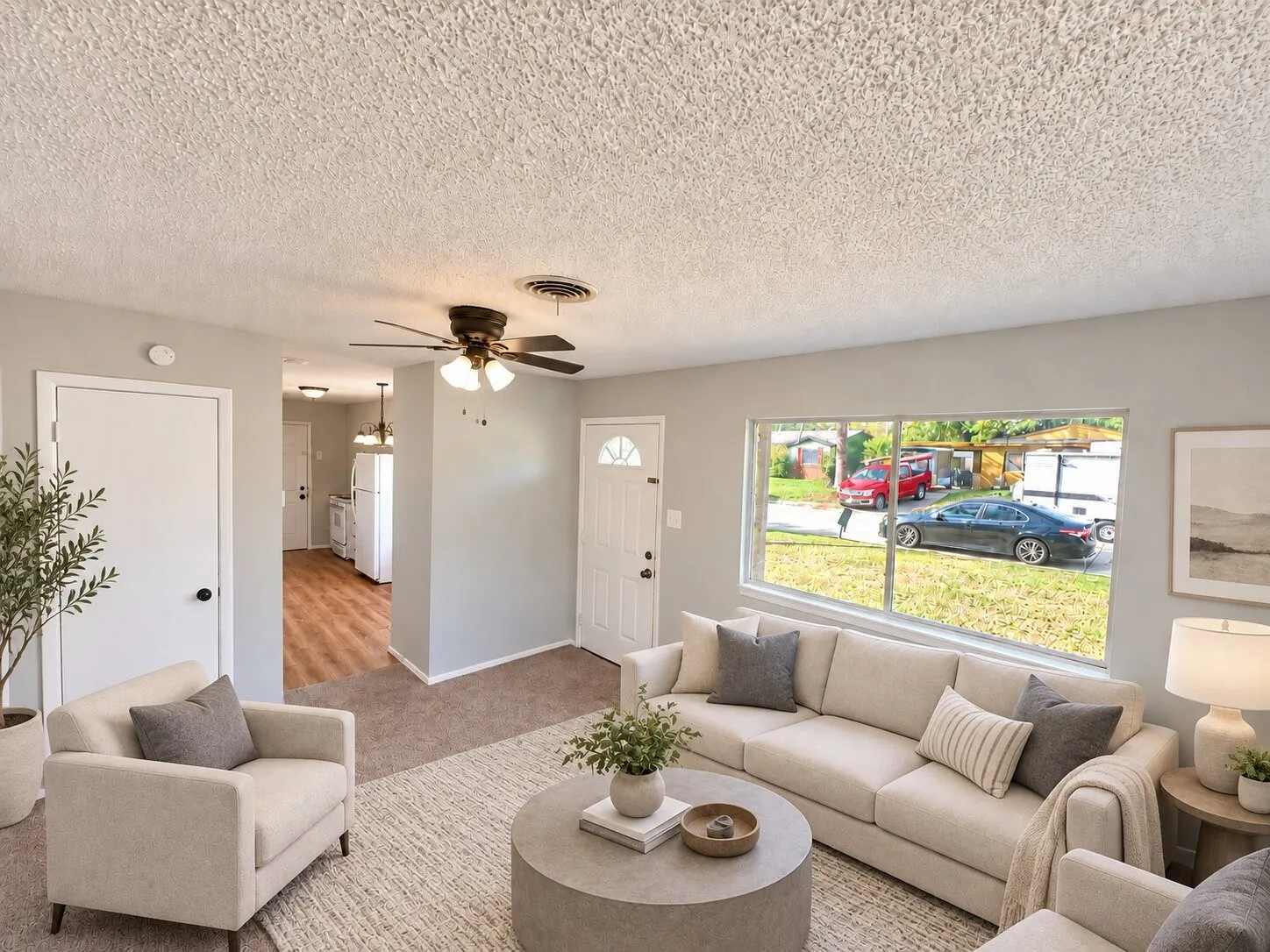 Interior space featuring neutral-toned wall paint, a large single-pane window, carpeted flooring, and a ceiling-mounted fan with integrated lighting