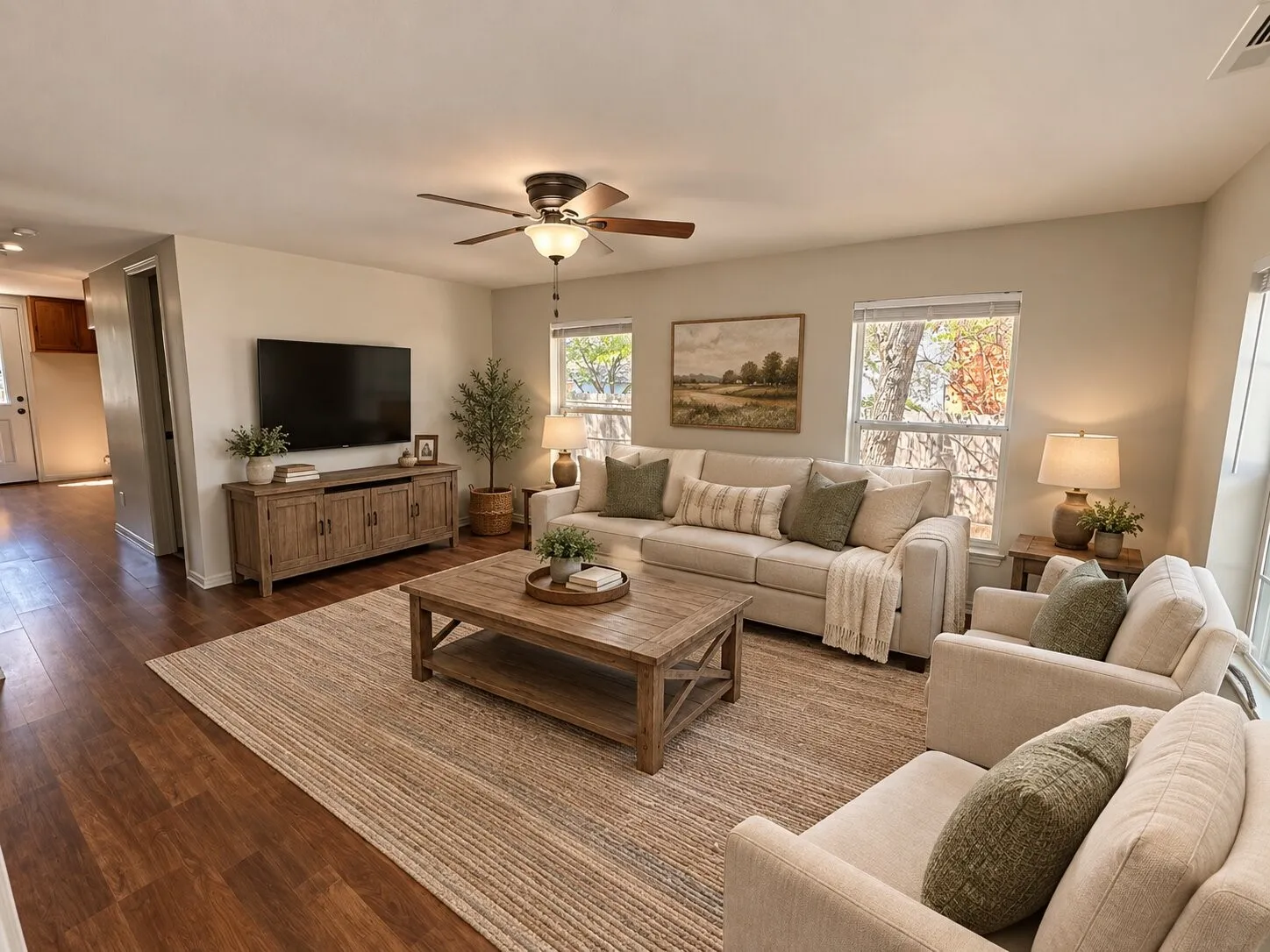 Living area featuring wood-finish flooring, light-toned wall paint, a ceiling fan with integrated lighting, and multiple windows