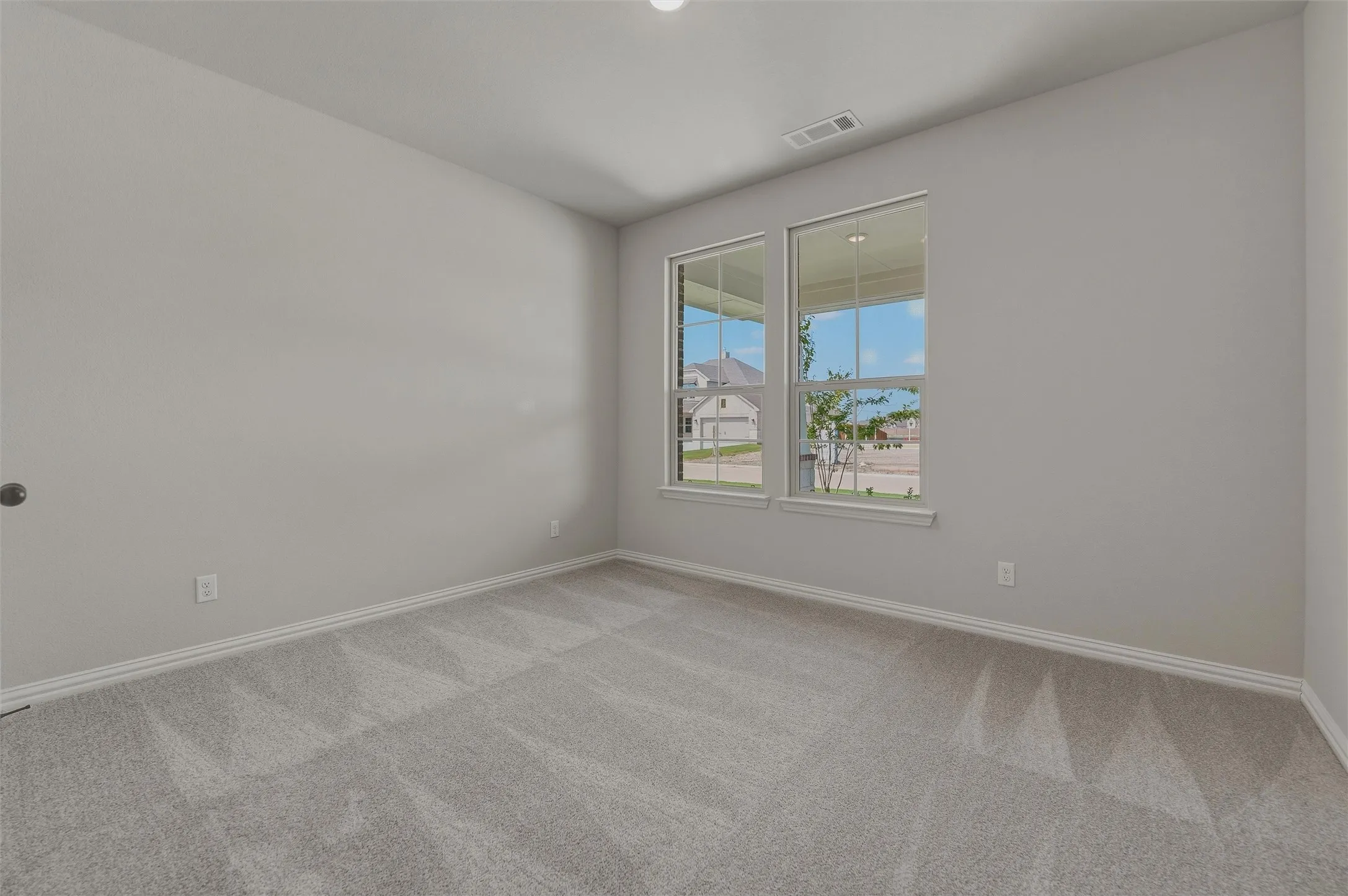 Light gray walls, patterned carpet flooring, and two double-hung windows