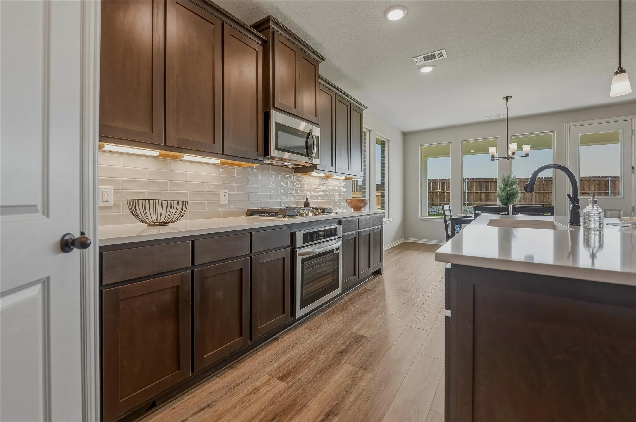 Dark wood-finish cabinetry, light-toned countertops, stainless steel appliances, and wood-finish flooring