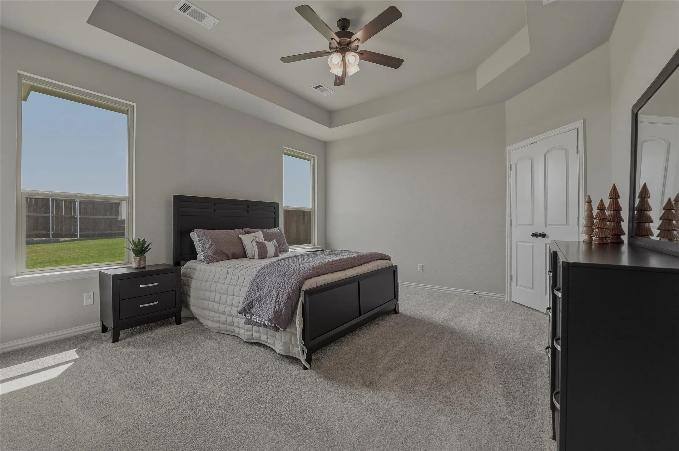 Carpeted room with a tray ceiling and a ceiling fan