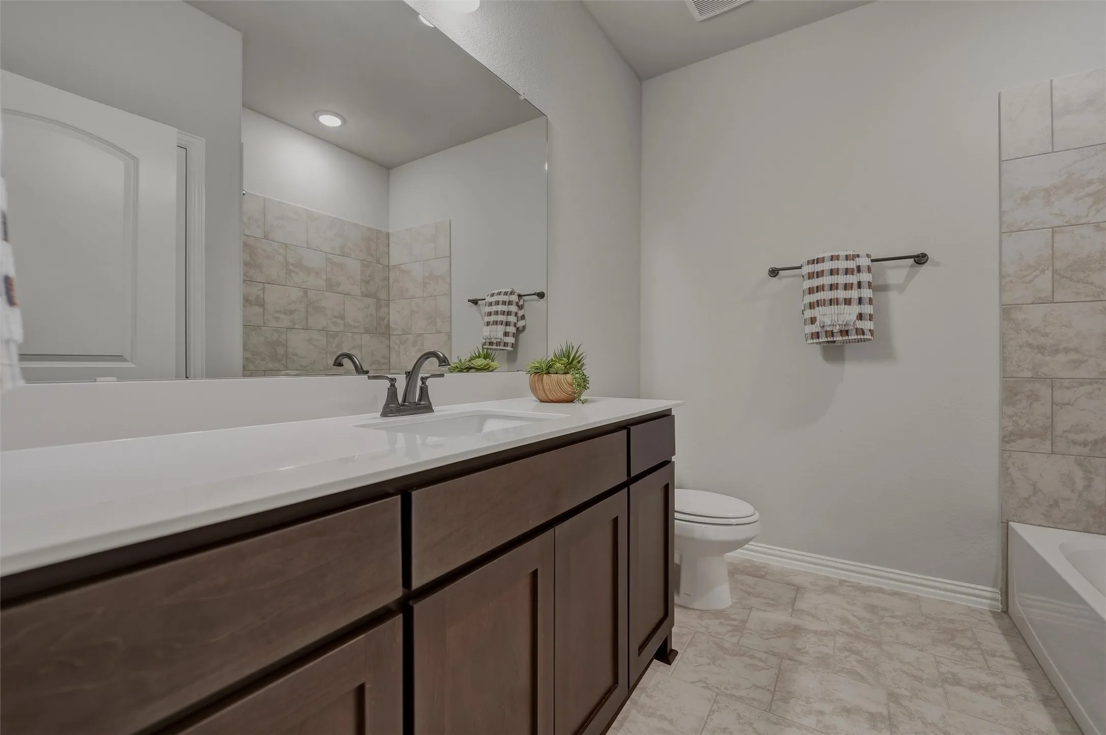 Wood-finish vanity with a white countertop and undermount sink