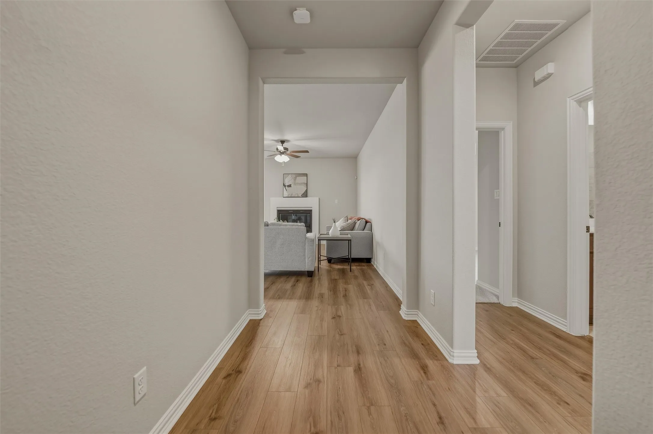 Light wood-finish flooring extending through the hallway and living area