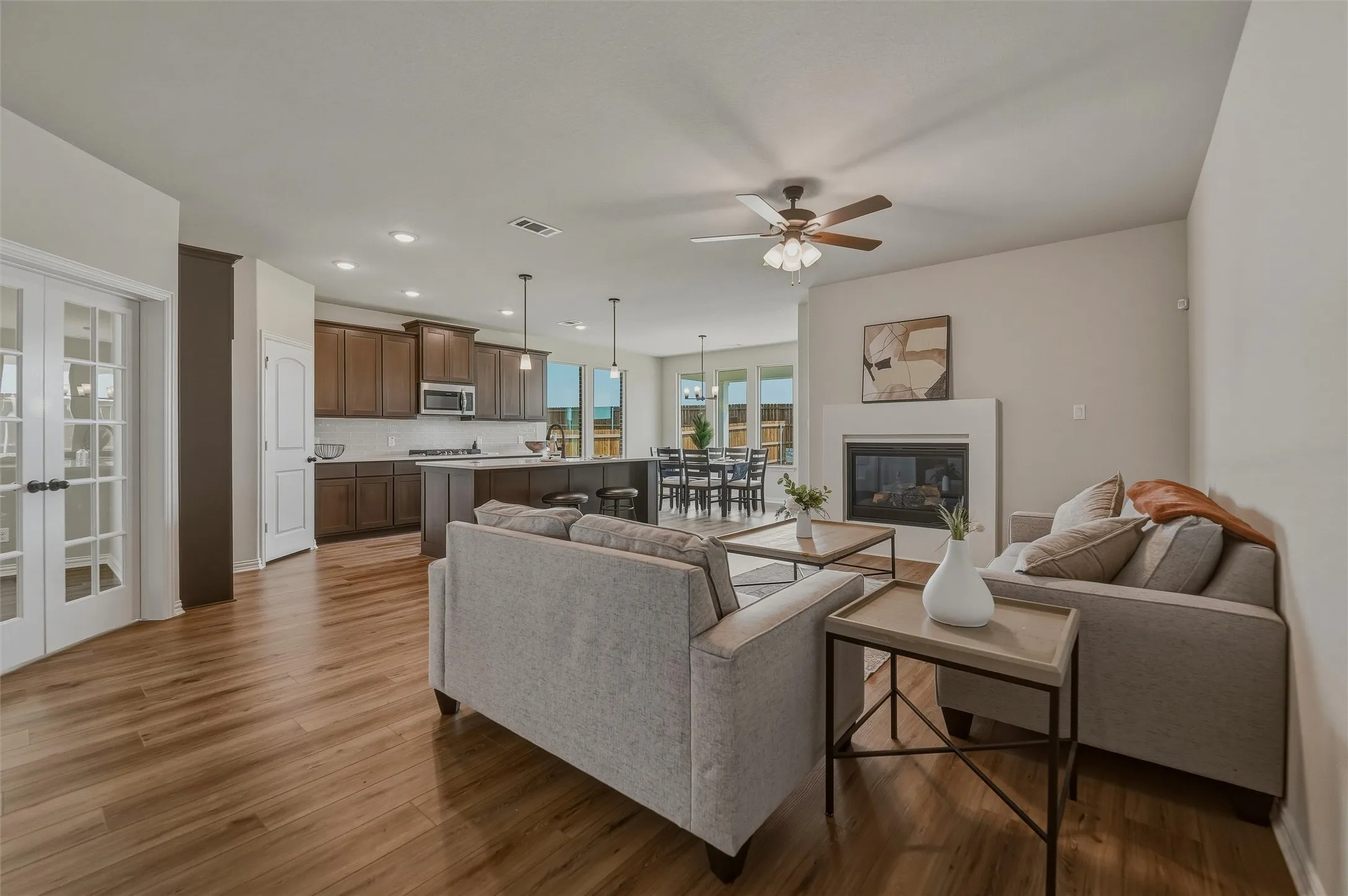 Open-concept living space featuring wood-finish flooring, a fireplace, and a ceiling fan