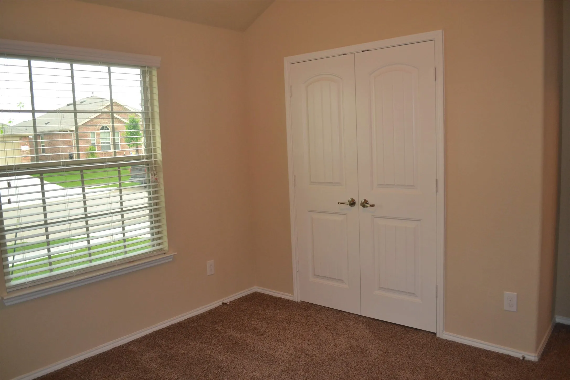 Interior space featuring vaulted ceilings, double-panel closet doors with satin nickel hardware, and a single-pane window with horizontal blinds