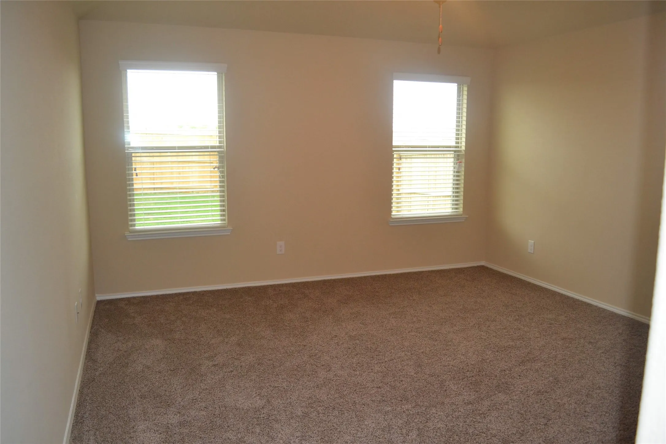 Neutral-toned room featuring neutral carpeting and two windows with horizontal blinds