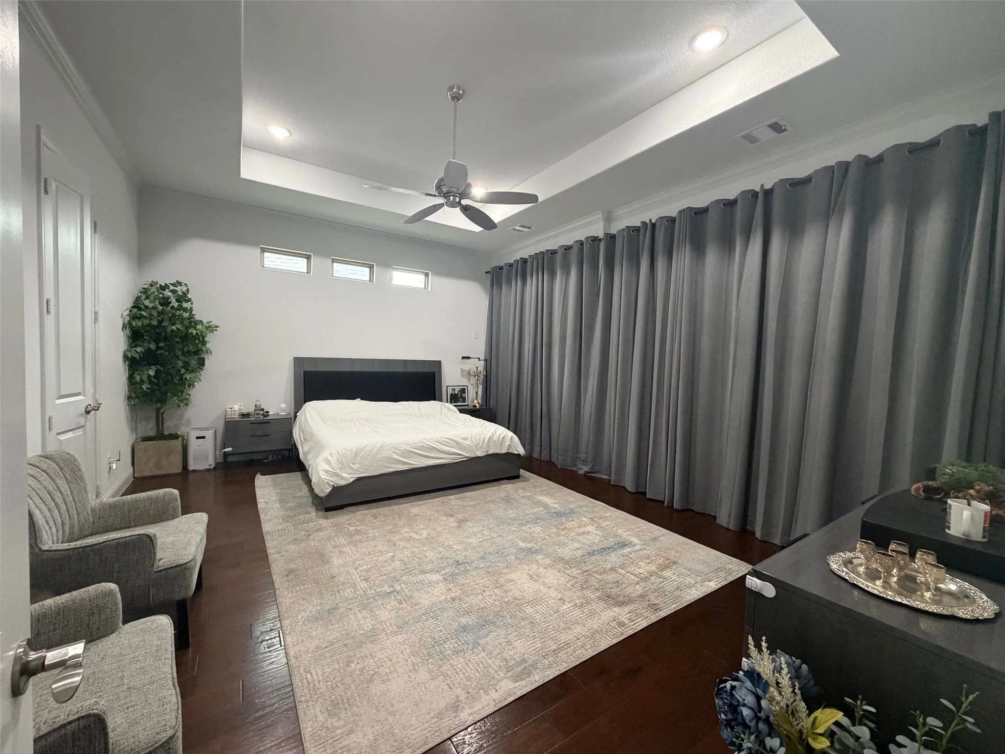 Tray ceiling with recessed lighting, ceiling fan, wood-finish flooring, and high-placed transom windows