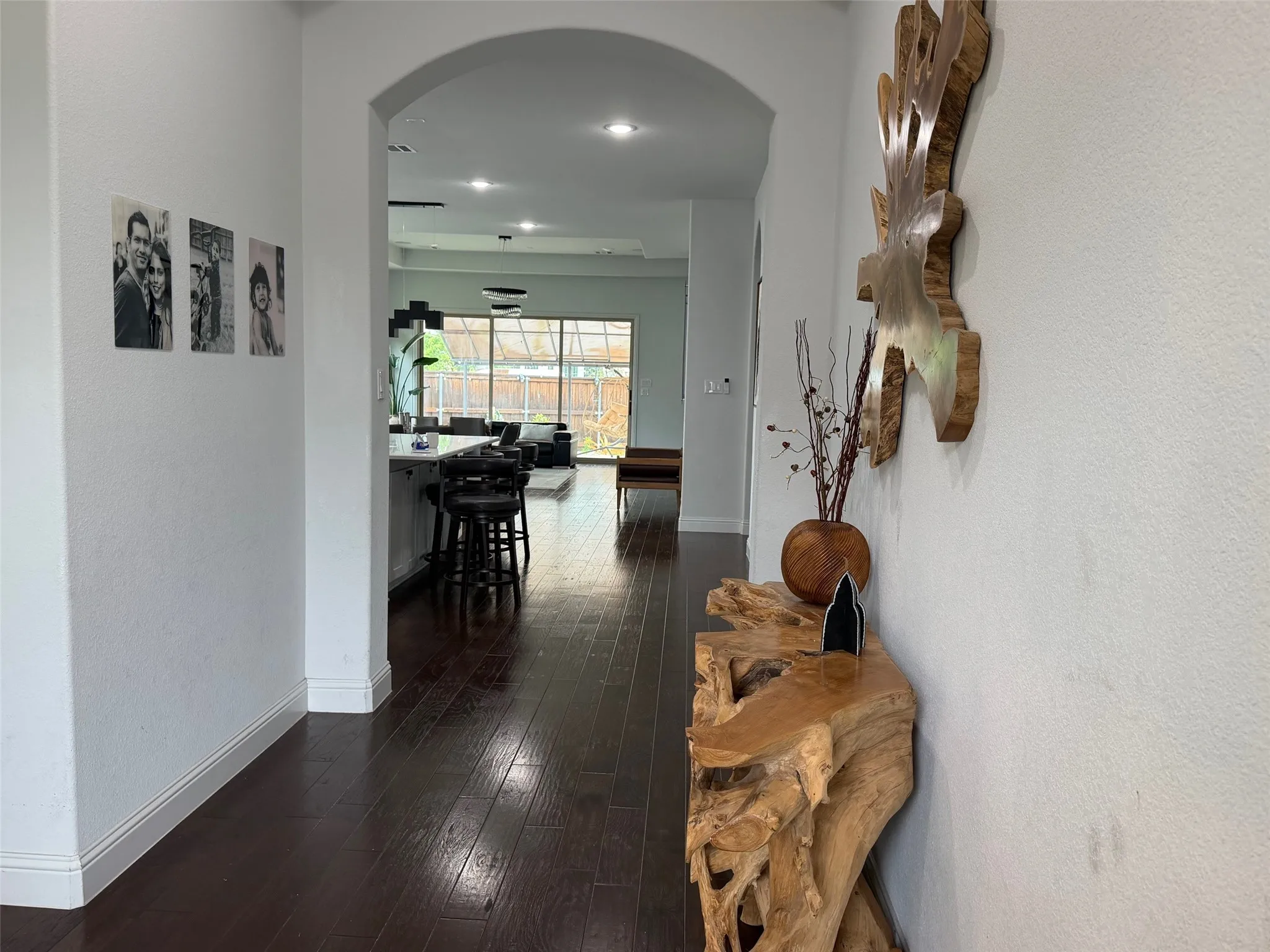 Interior hallway featuring arched architectural detail, dark wood-finish flooring, and recessed ceiling lighting