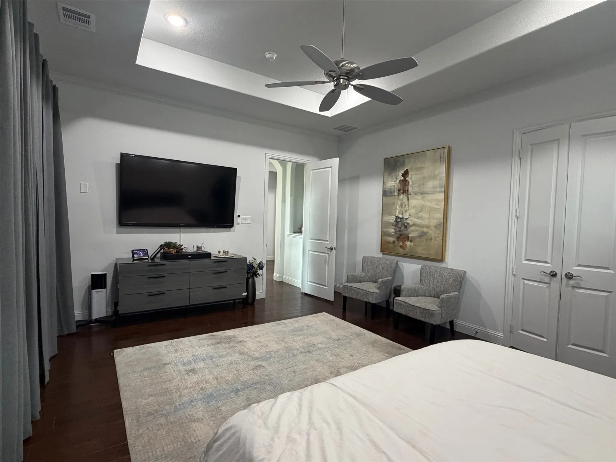 Tray ceiling featuring recessed lighting and a brushed-nickel ceiling fan, accompanied by wood-finish flooring and solid-core paneled doors