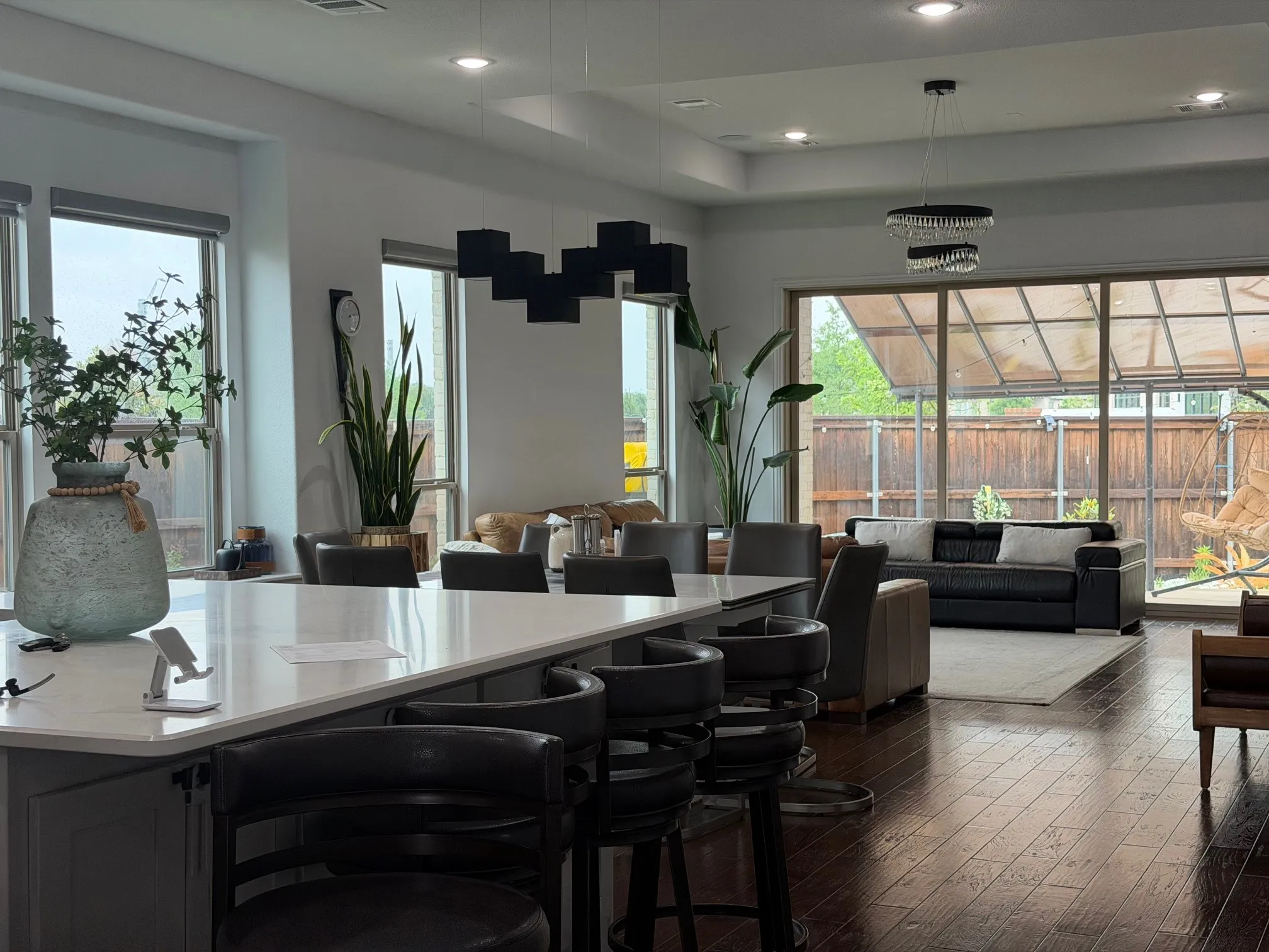Kitchen featuring a quartz countertop island with waterfall edge, wood-finish flooring, recessed lighting, and multiple geometric and tiered chandeliers
