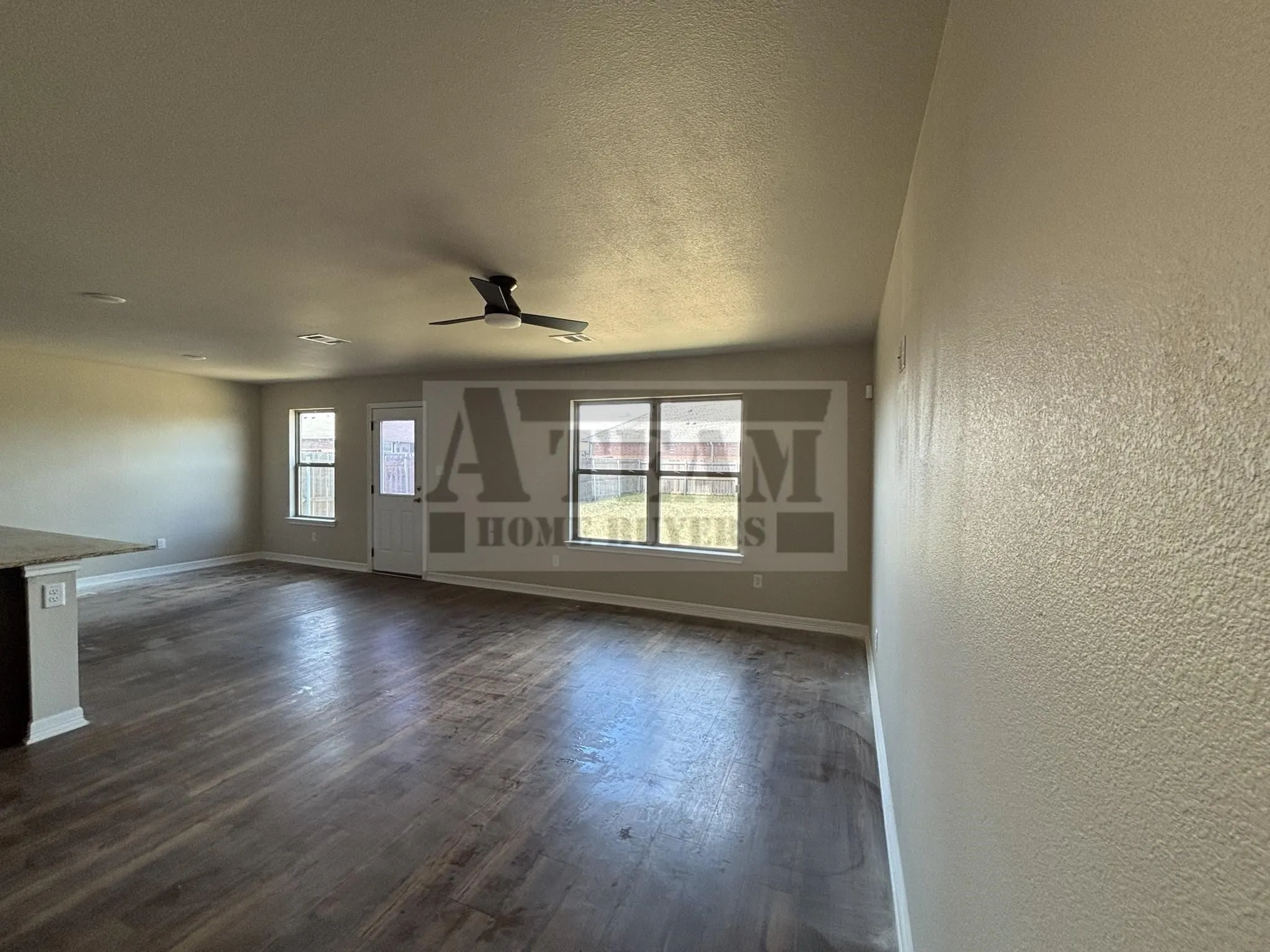 Open interior featuring wood-finish flooring, recessed lighting, a matte black ceiling fan, and large windows