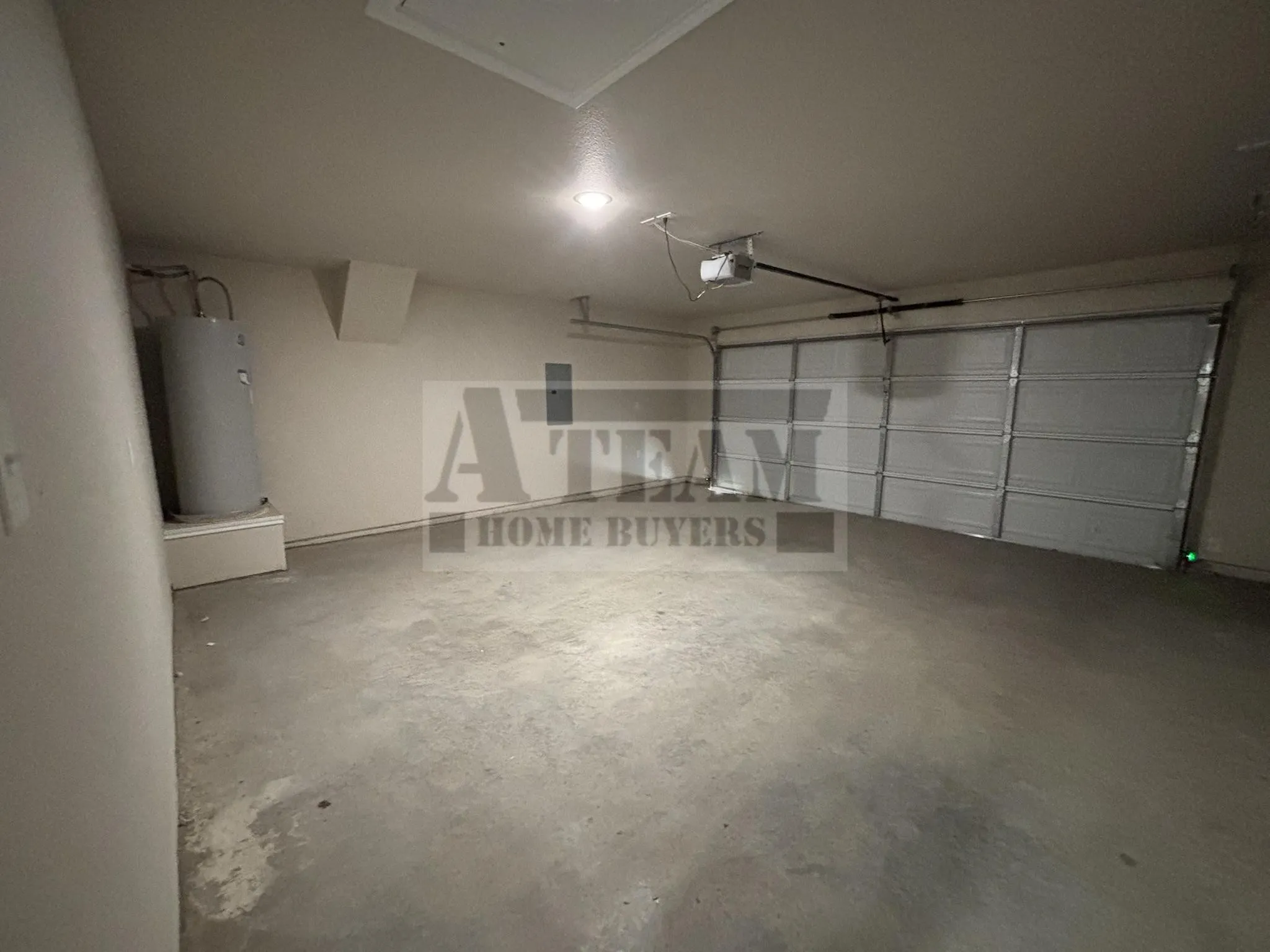 Attached garage featuring a multi-panel roll-up door, concrete flooring, and ceiling-mounted automatic door opener
