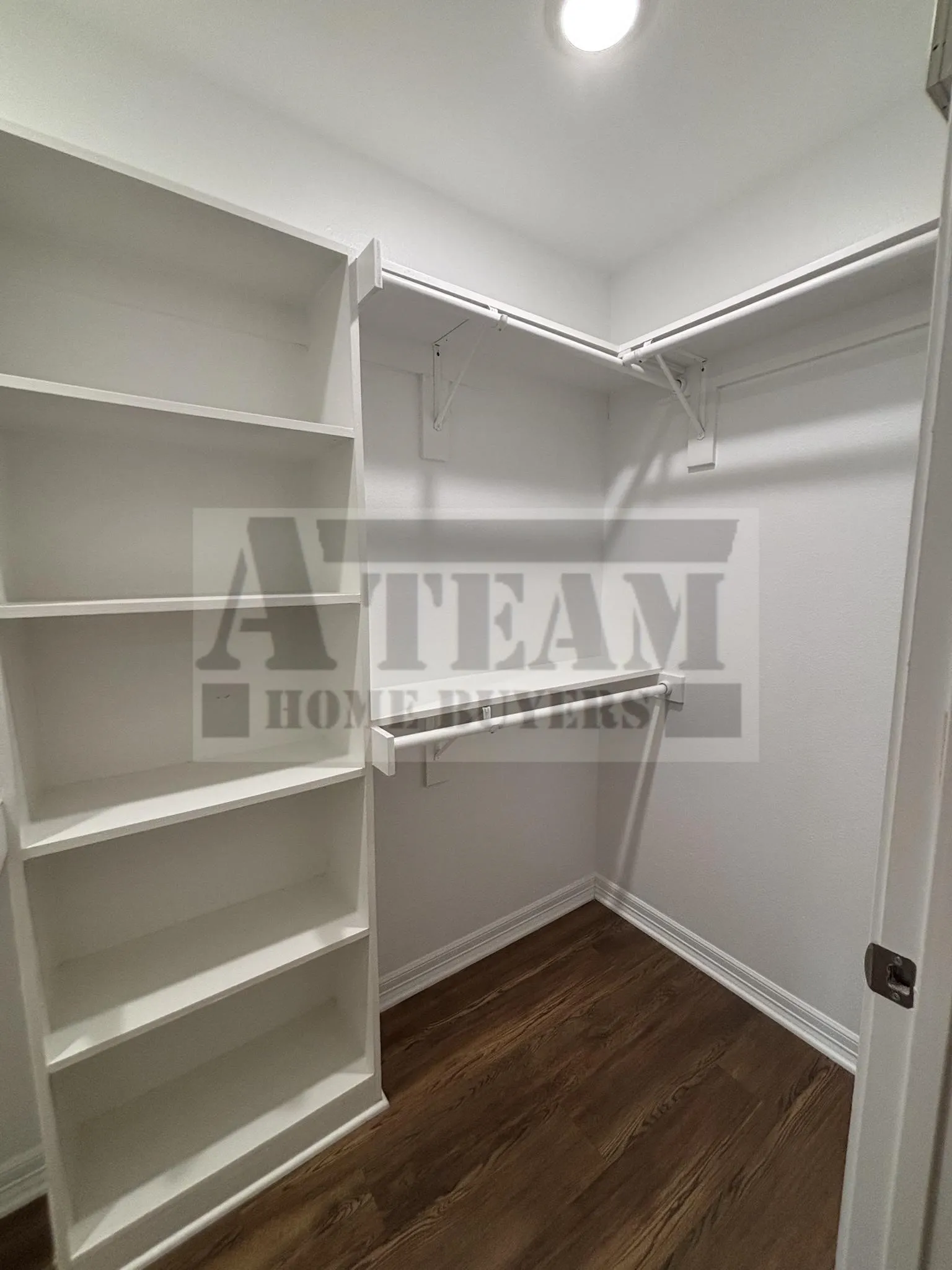 Walk-in closet featuring built-in white shelving, custom hanging rods, recessed lighting, and wood-finish flooring