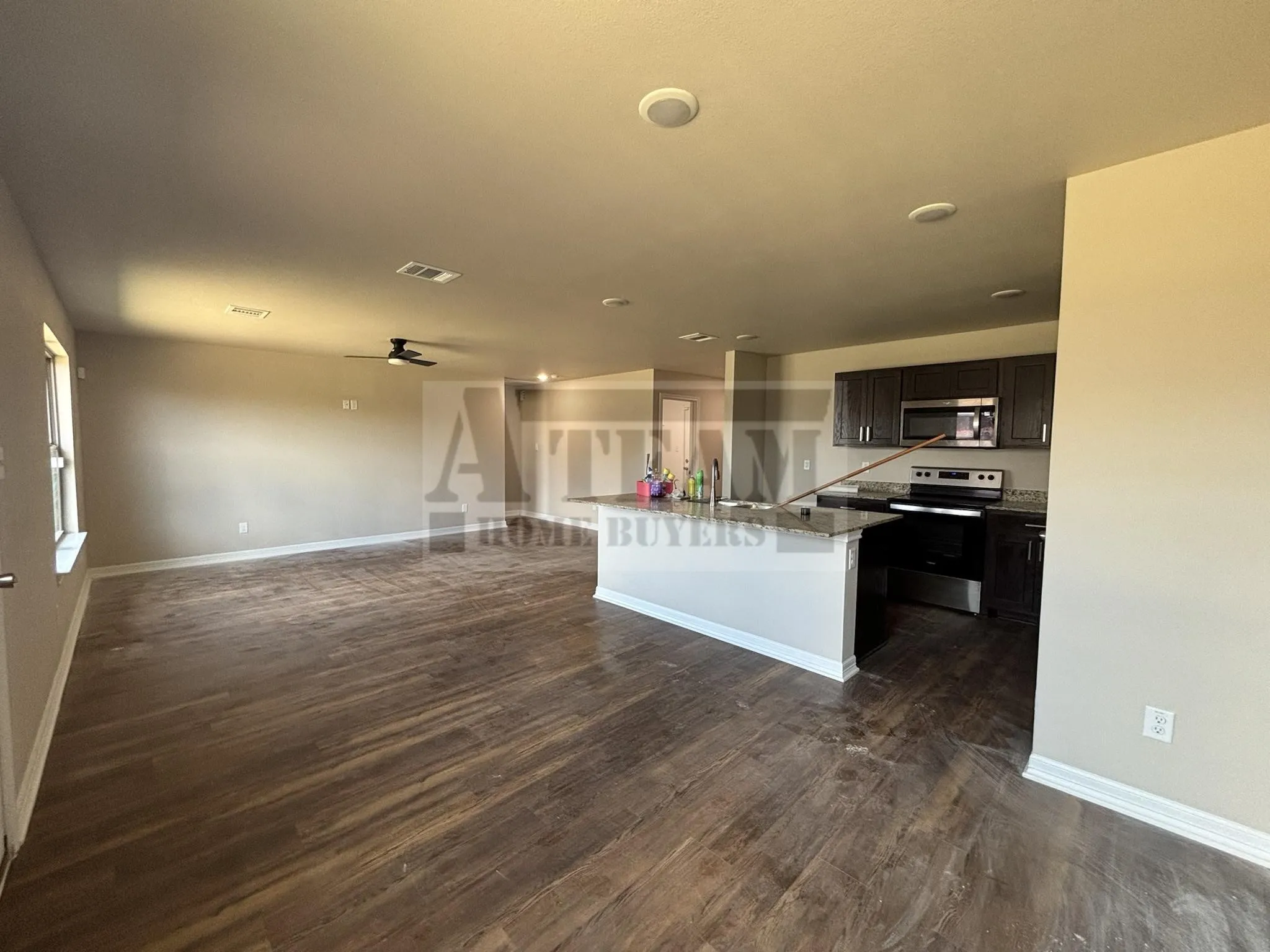 Open-concept space featuring wood-finish flooring, recessed lighting, dark cabinetry, stone-surface countertops, and a kitchen island