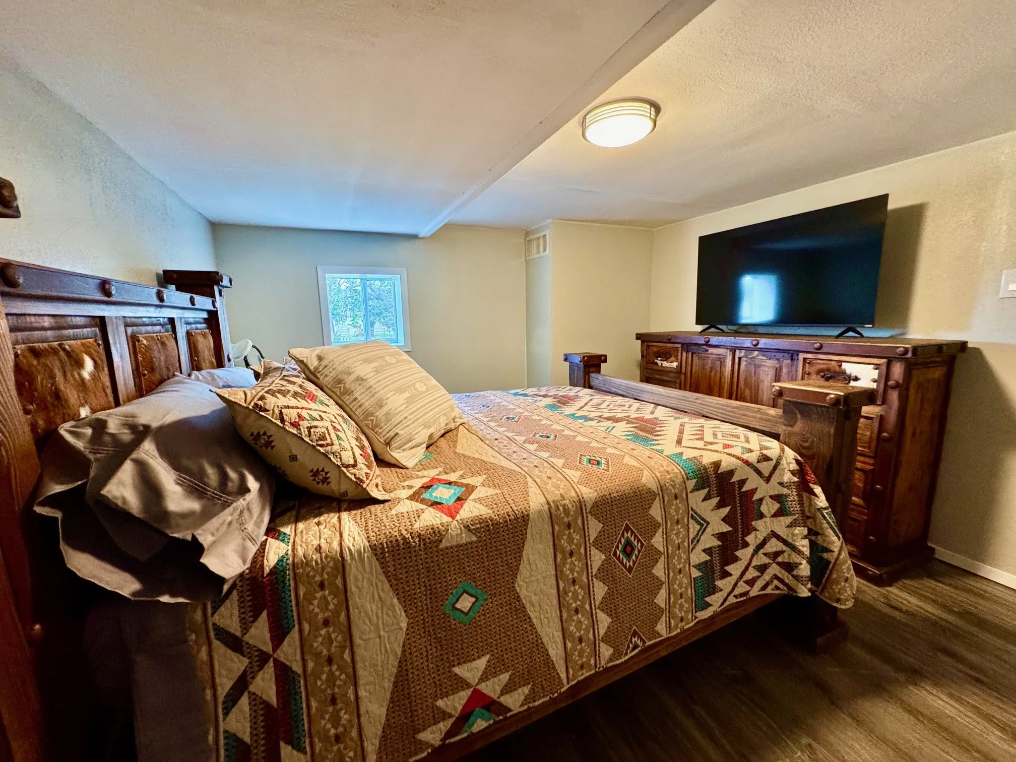 Bedroom with dark wood-style floors, a textured wall, and a textured ceiling