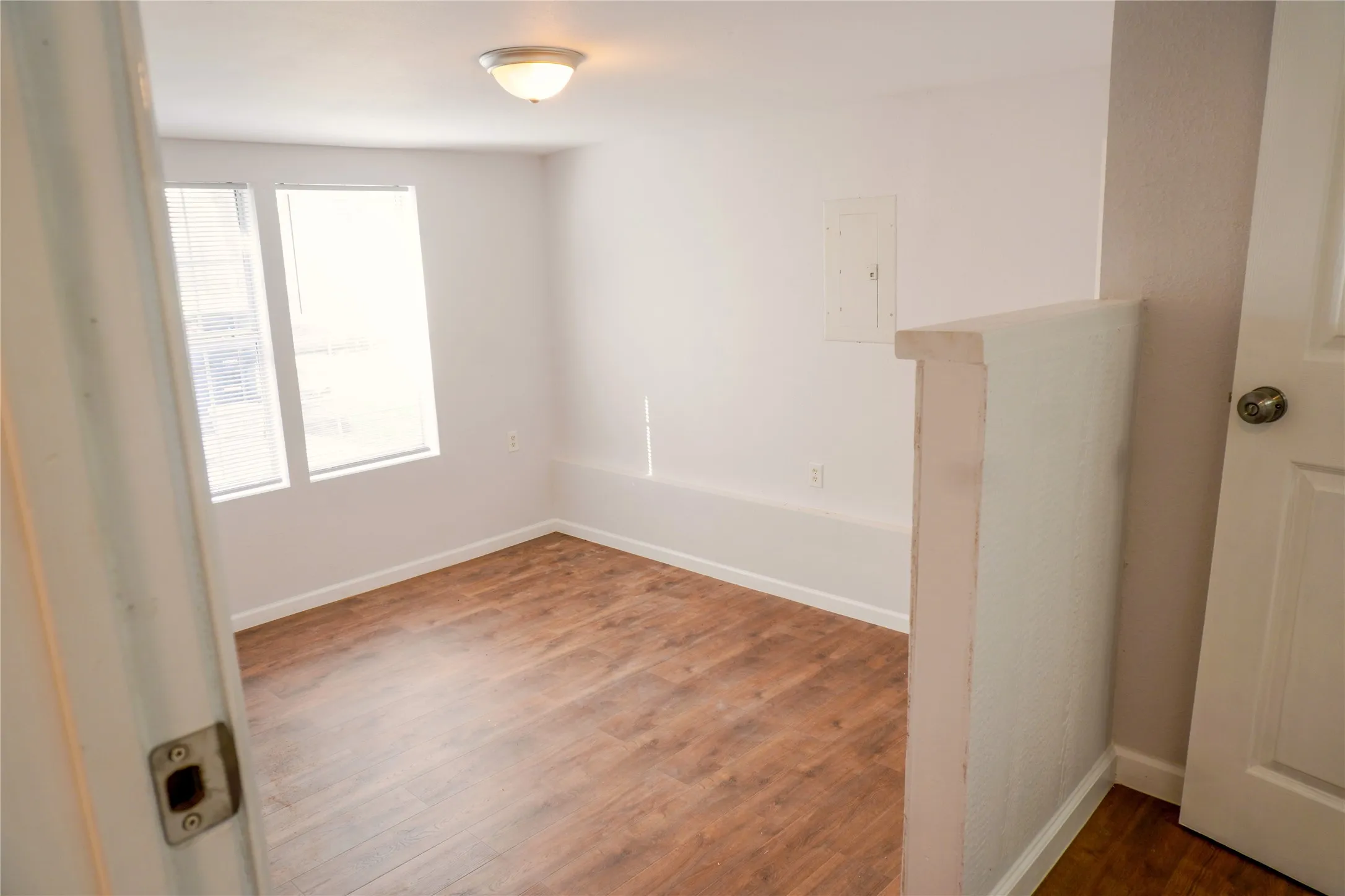 Room featuring wood-finish flooring, dual windows, and a flush-mount ceiling light fixture
