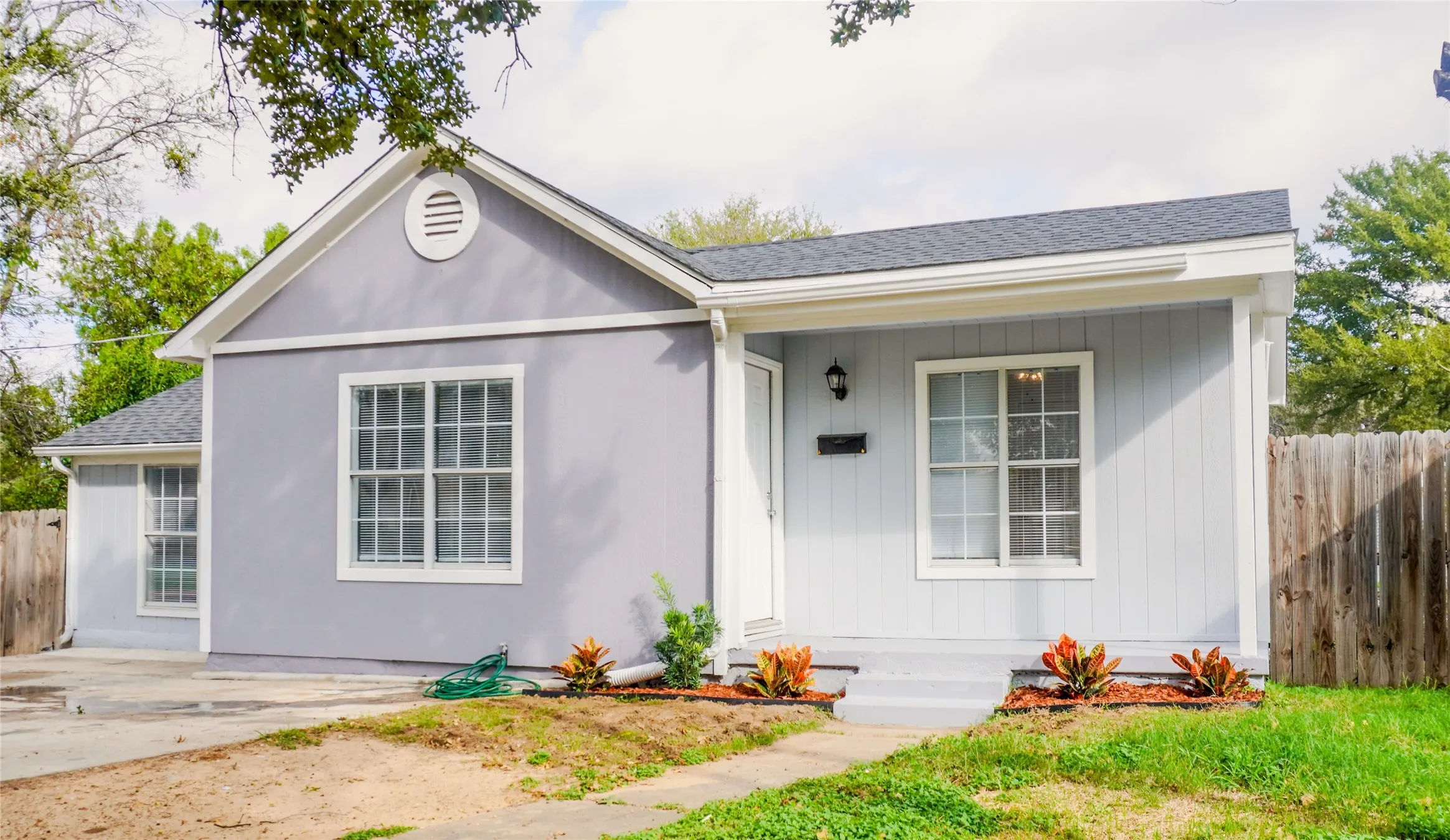 Exterior featuring light-toned vertical siding, a gabled roofline, multi-pane windows, and a covered front entry porch