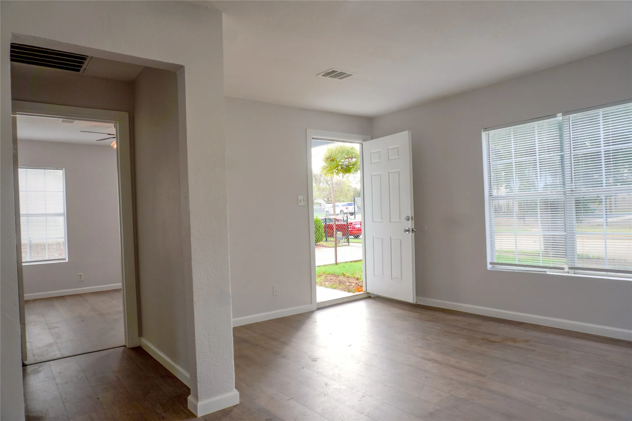 Neutral-toned interior featuring wood-finish flooring, multi-pane windows with blinds, and a six-panel exterior entry door