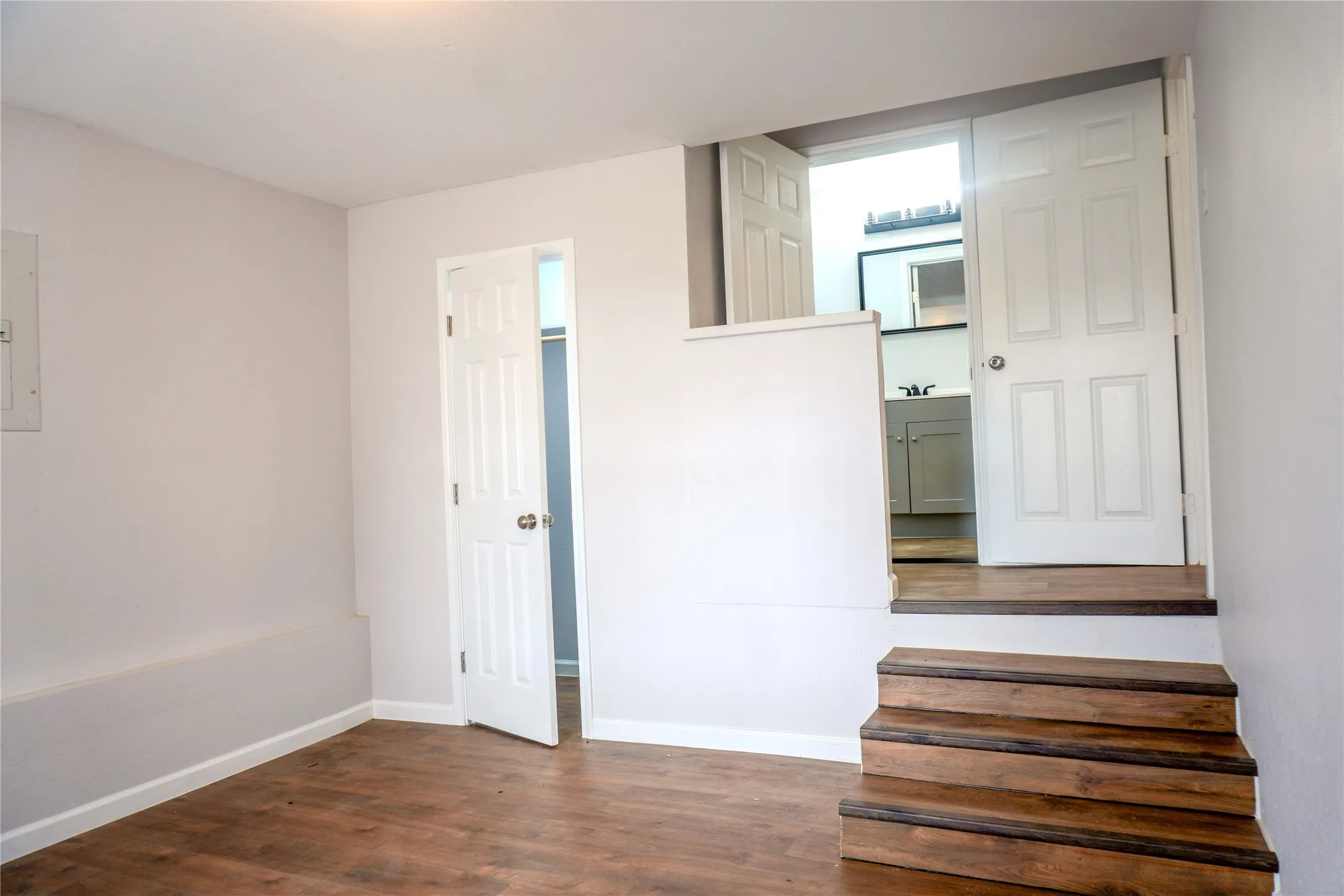 Wood-finish flooring, staircase with stained wood treads, two interior paneled doors, and built-in closet access
