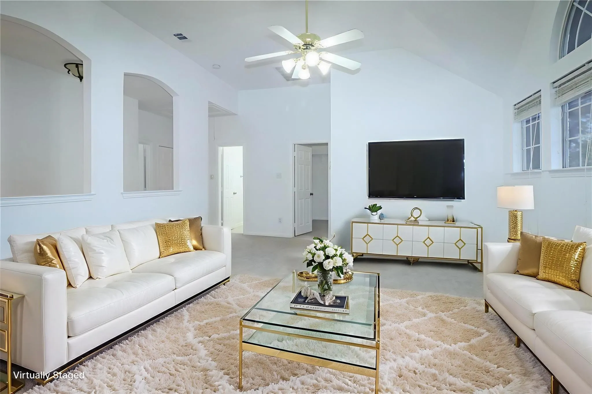 Vaulted ceilings featuring recessed arch niches, neutral carpeting, a central ceiling fan, and multi-pane windows