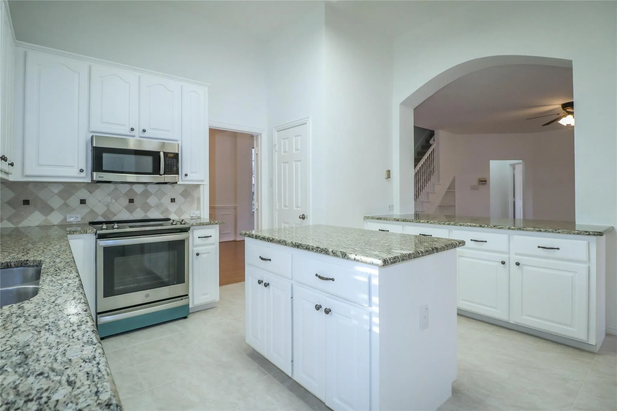 Kitchen featuring white cabinetry, stone countertops, a center island, stainless steel appliances, and a tiled backsplash