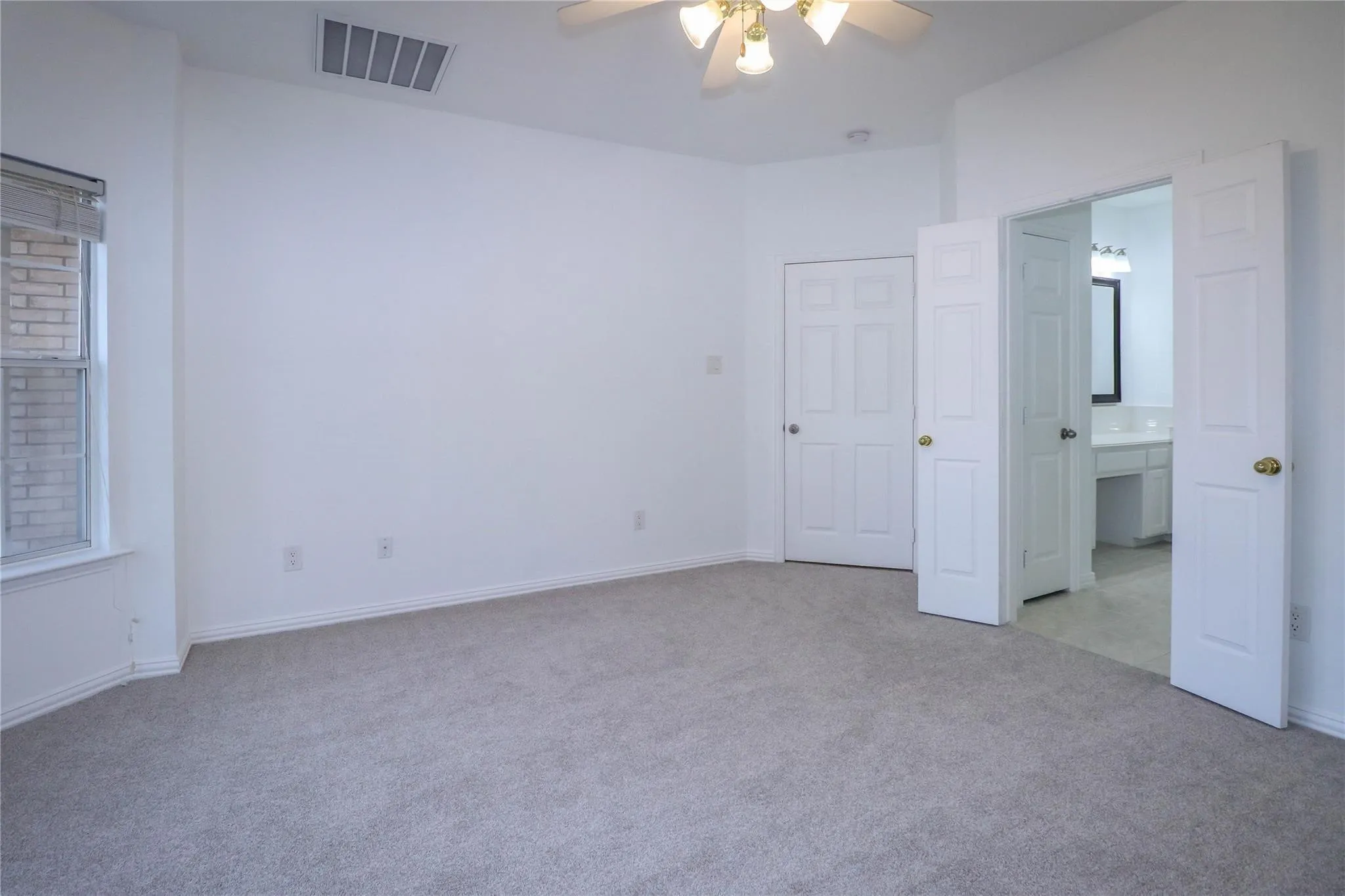 Neutral-toned wall-to-wall carpeting, multi-pane window, ceiling fan with integrated lighting, and white six-panel interior doors