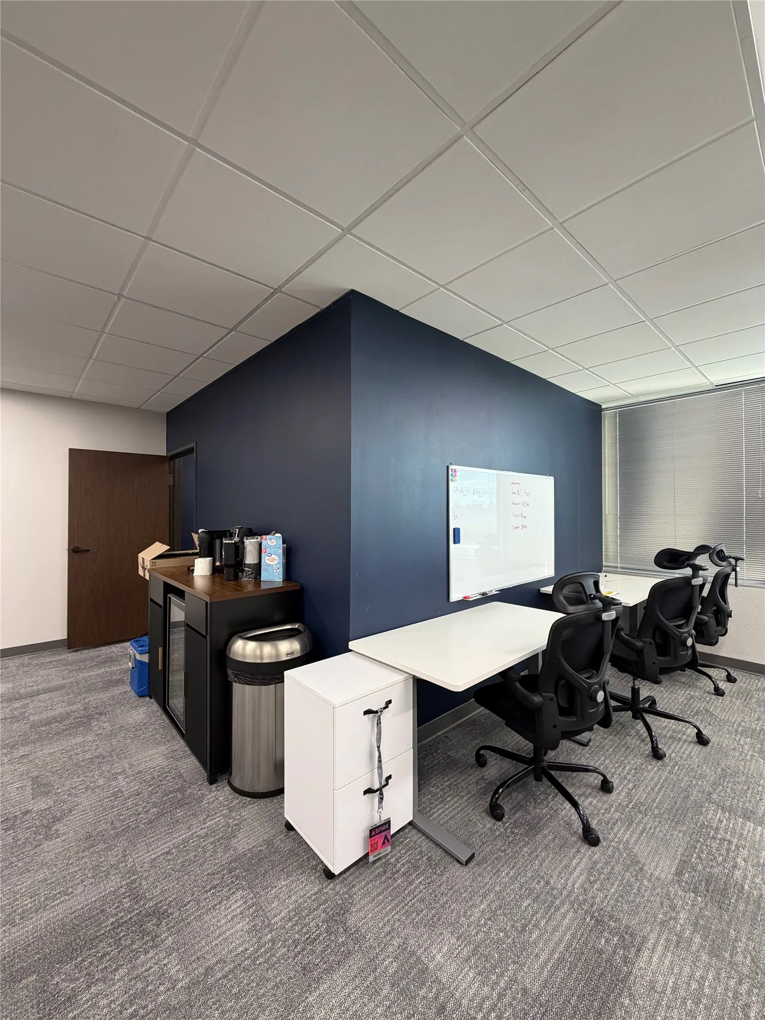 Neutral-toned carpeted flooring, drop ceiling with recessed lighting, accent wall, and horizontal window blinds